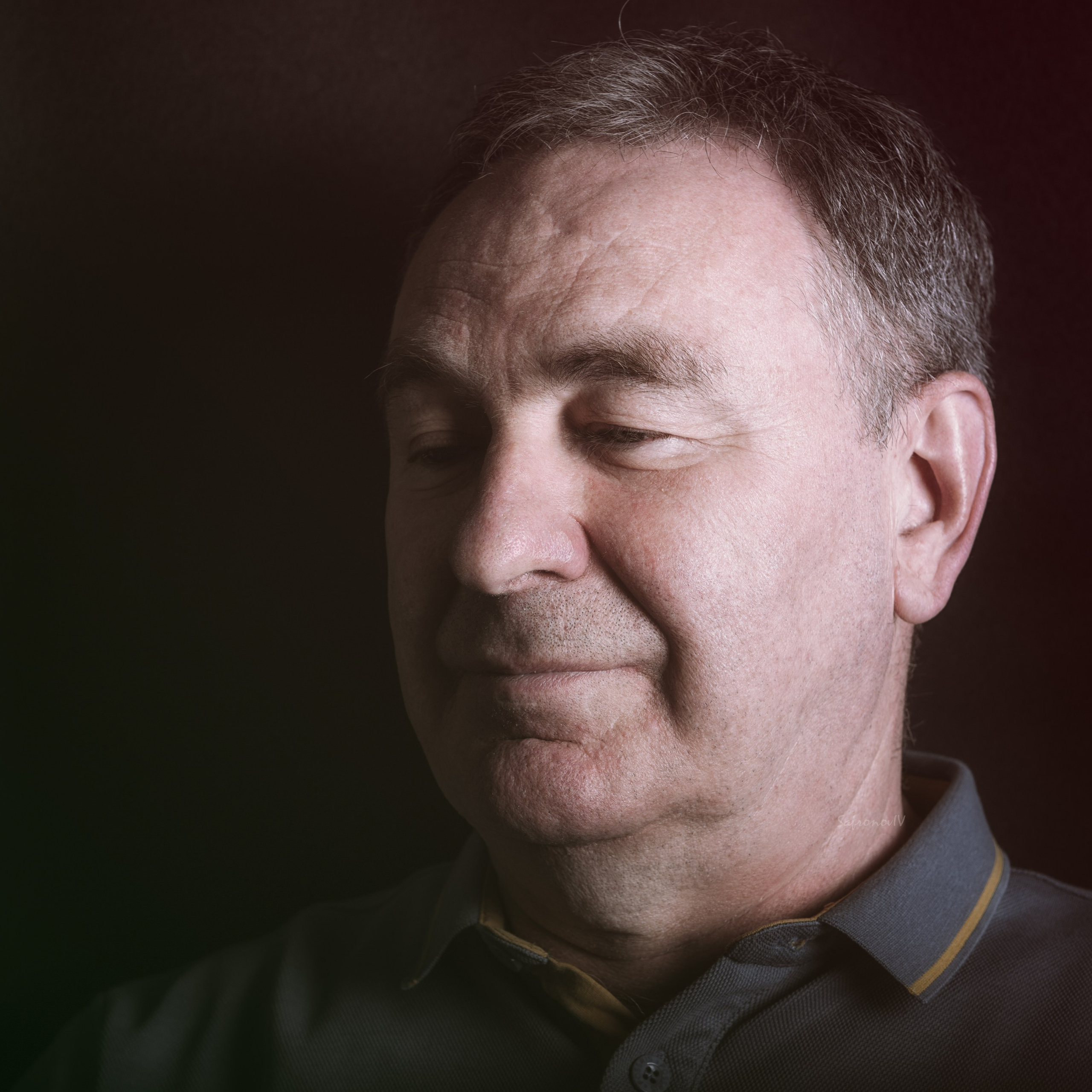 мужчина с закрытыми глазами, одетый в повседневную рубашку. Освещение мягкое, с акцентом на лице, что создает атмосферу спокойствия и задумчивости.Заголовок: «Момент размышления: портрет в мягких тонах»Ключевые слова: портрет, мужчина, повседневная рубашка, мягкое освещение, задумчивость, фотография.