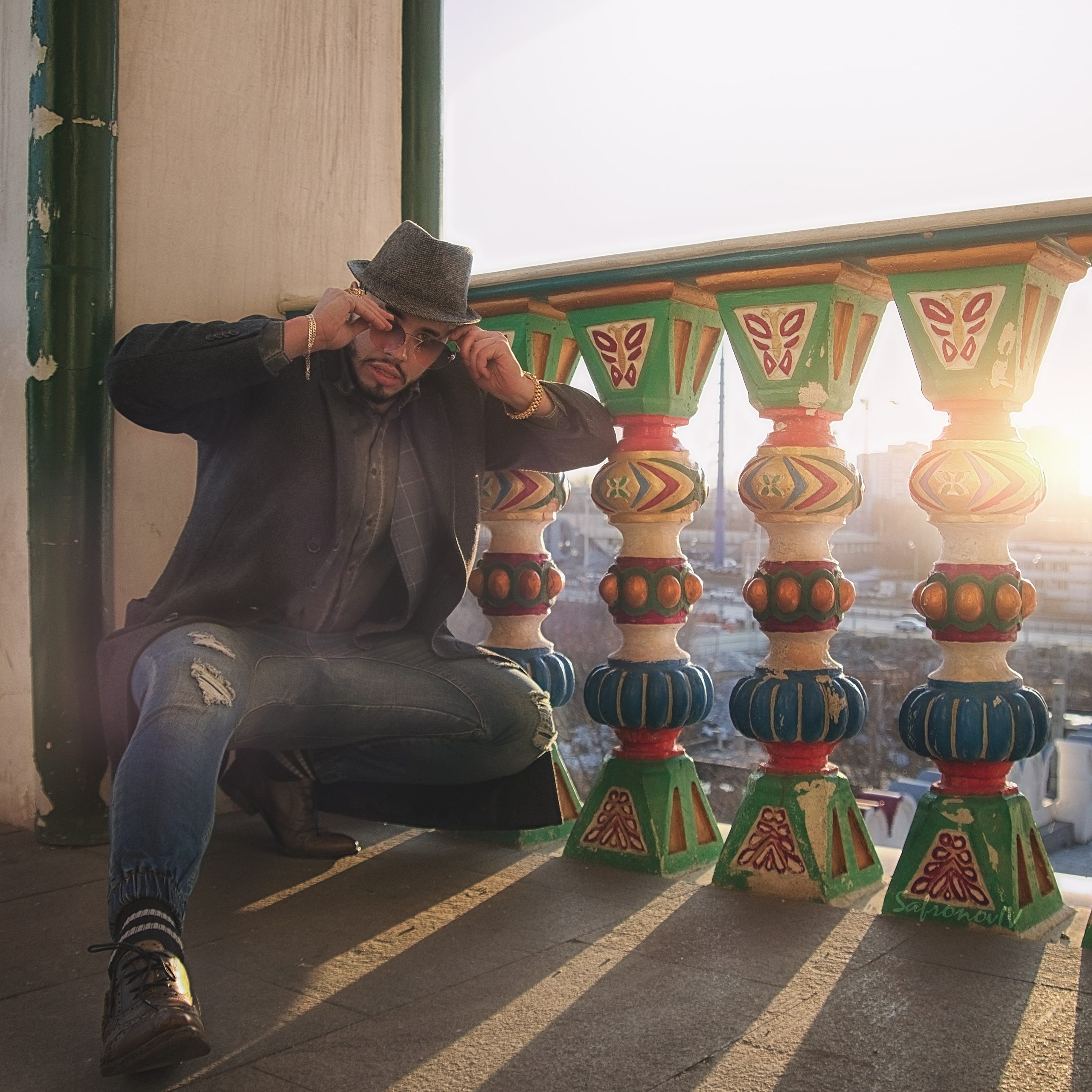 Модный мужчина на закате, рядом с забором