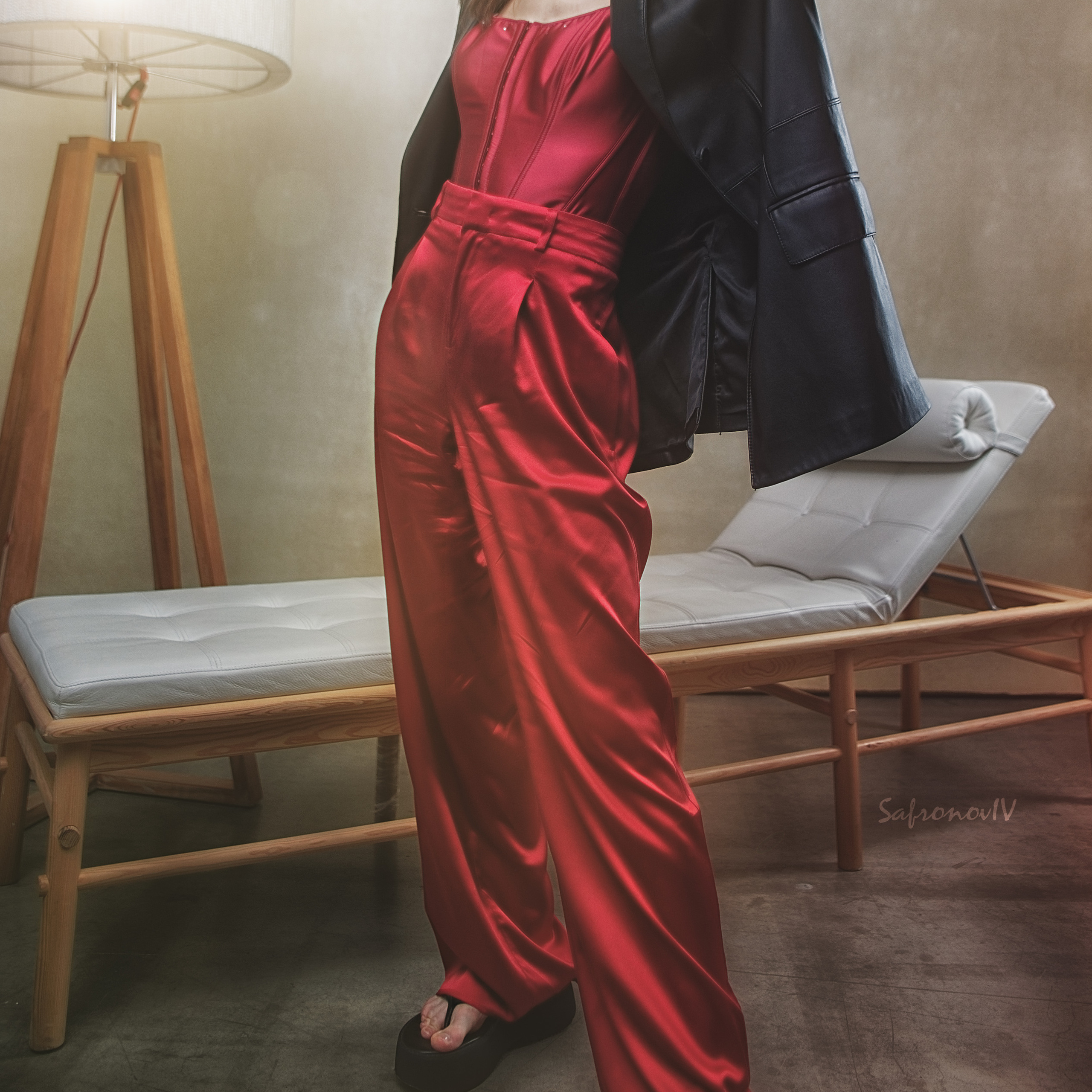 Девушка возле торшера в красных штанах и черной куртке