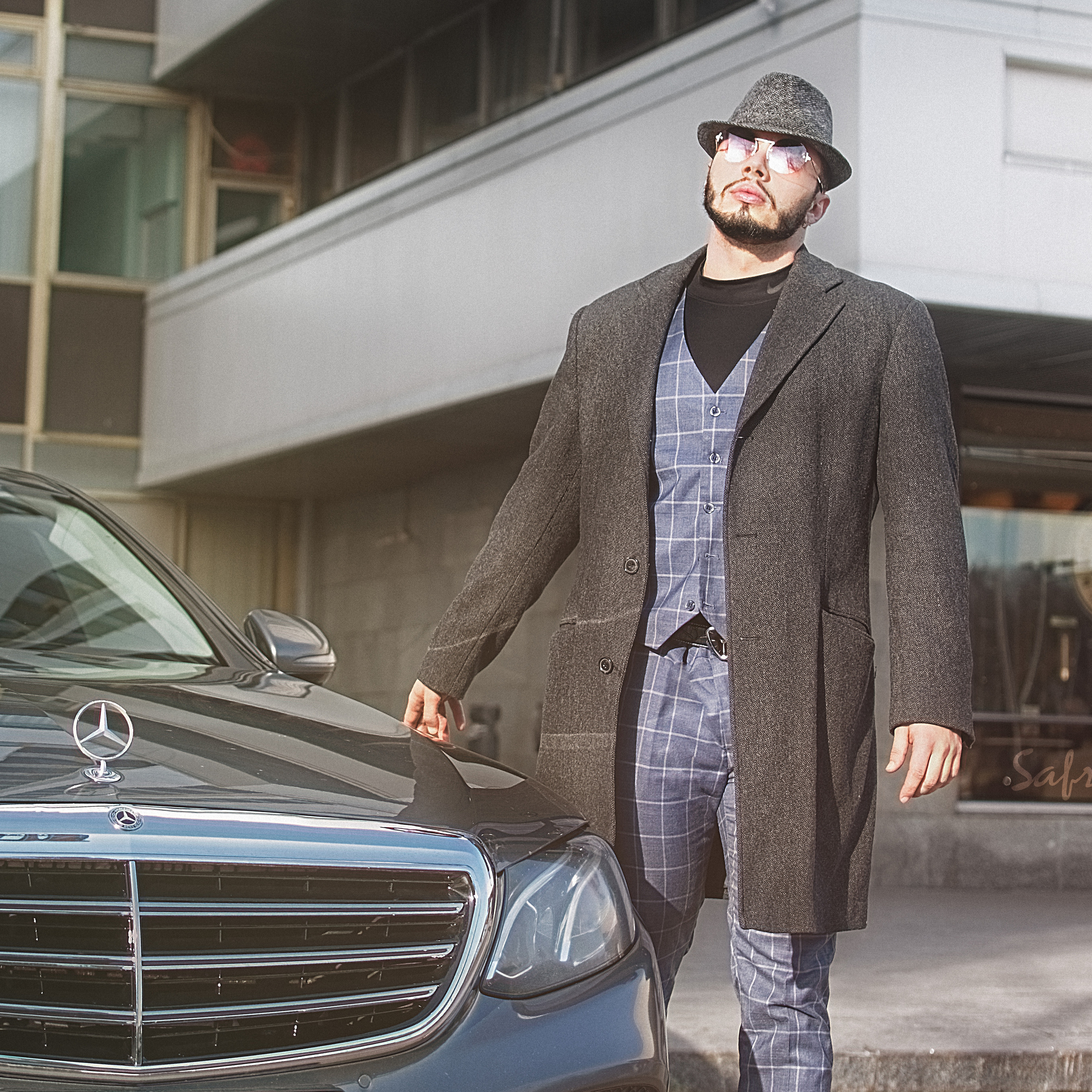 Парень возле машины в костюме и пальто