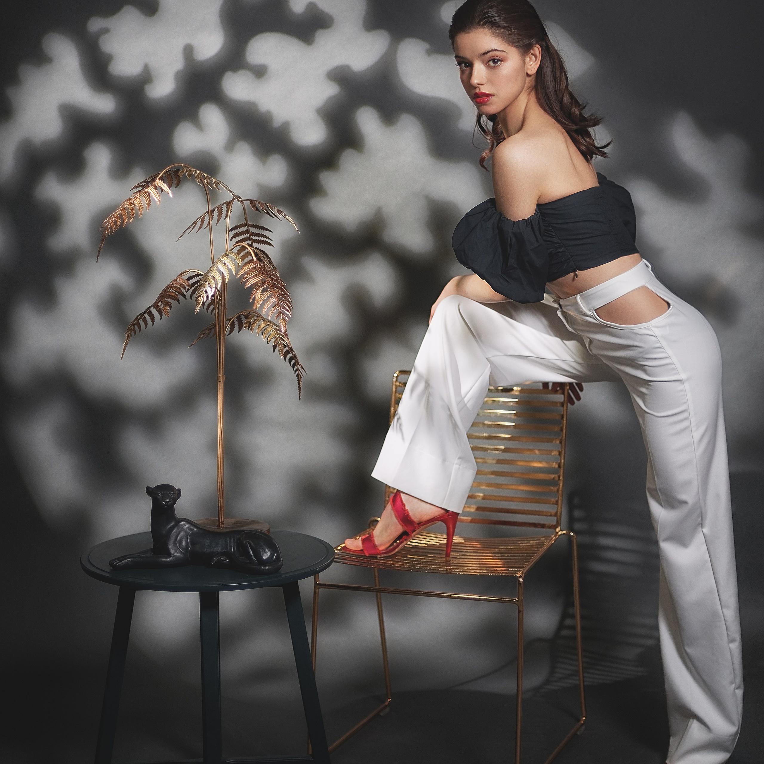 Девушка в белых брюках и черном топике в лучах прожектора