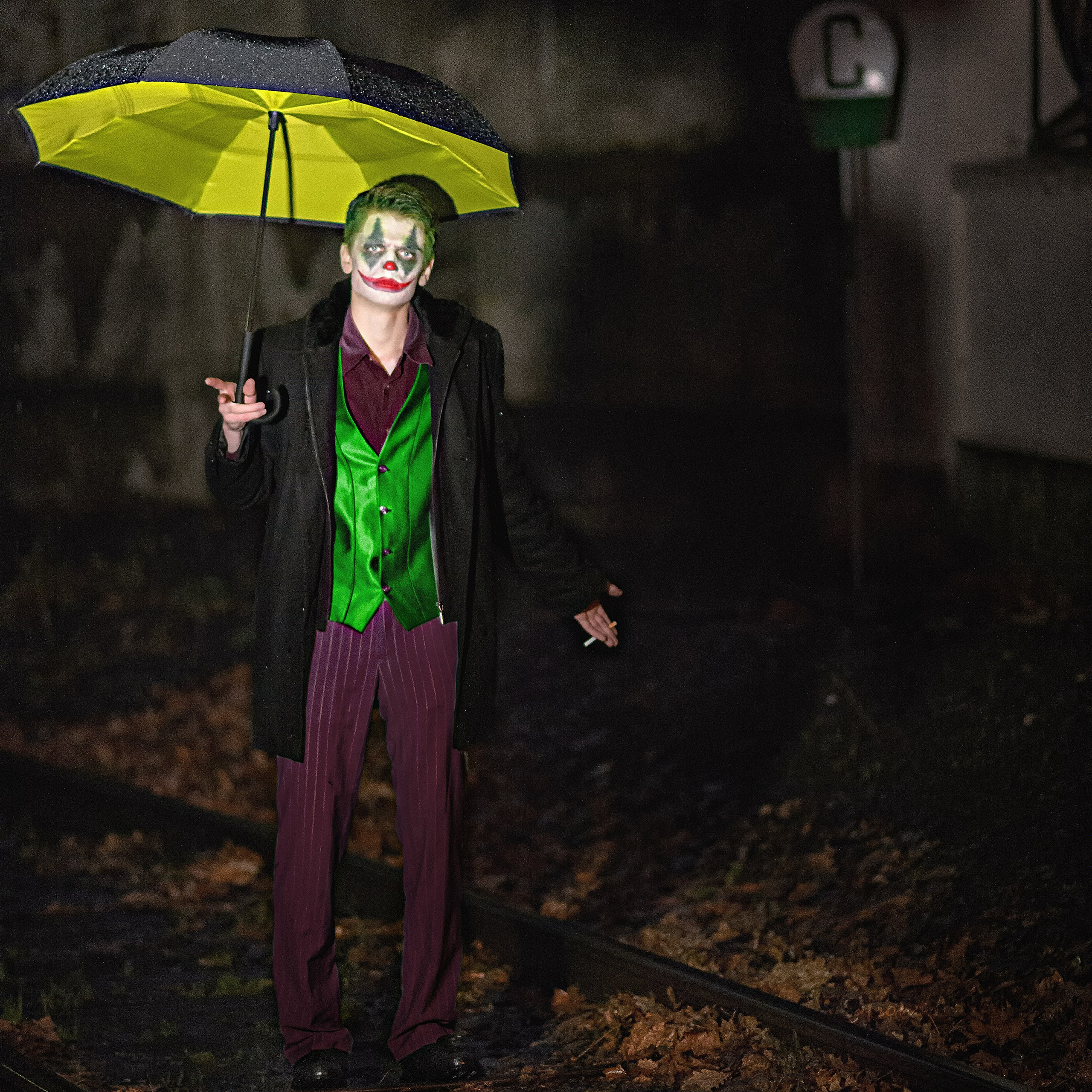Джокер стоит в луже на железнодорожных путях ночью на улицах города