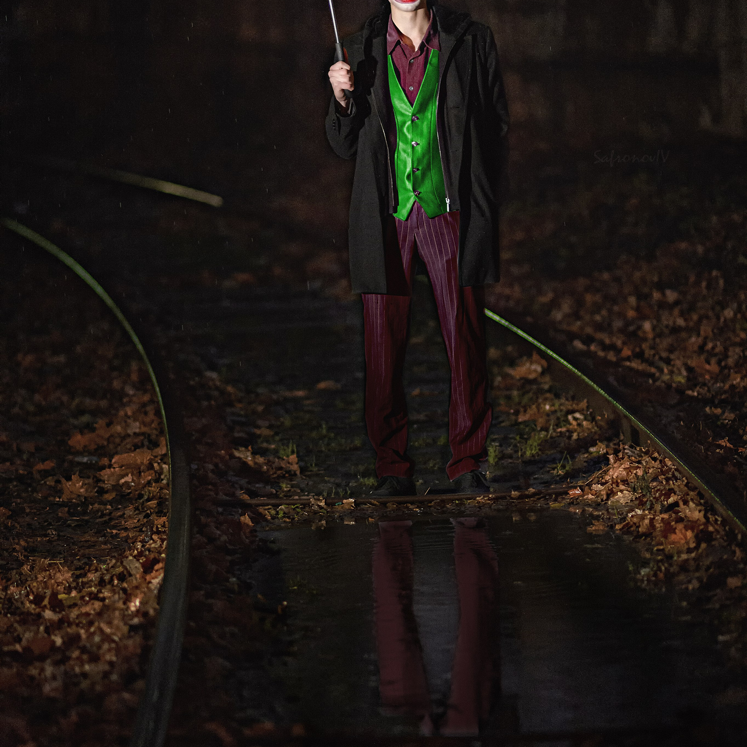 Джокер стоит под зонтом на рельсах