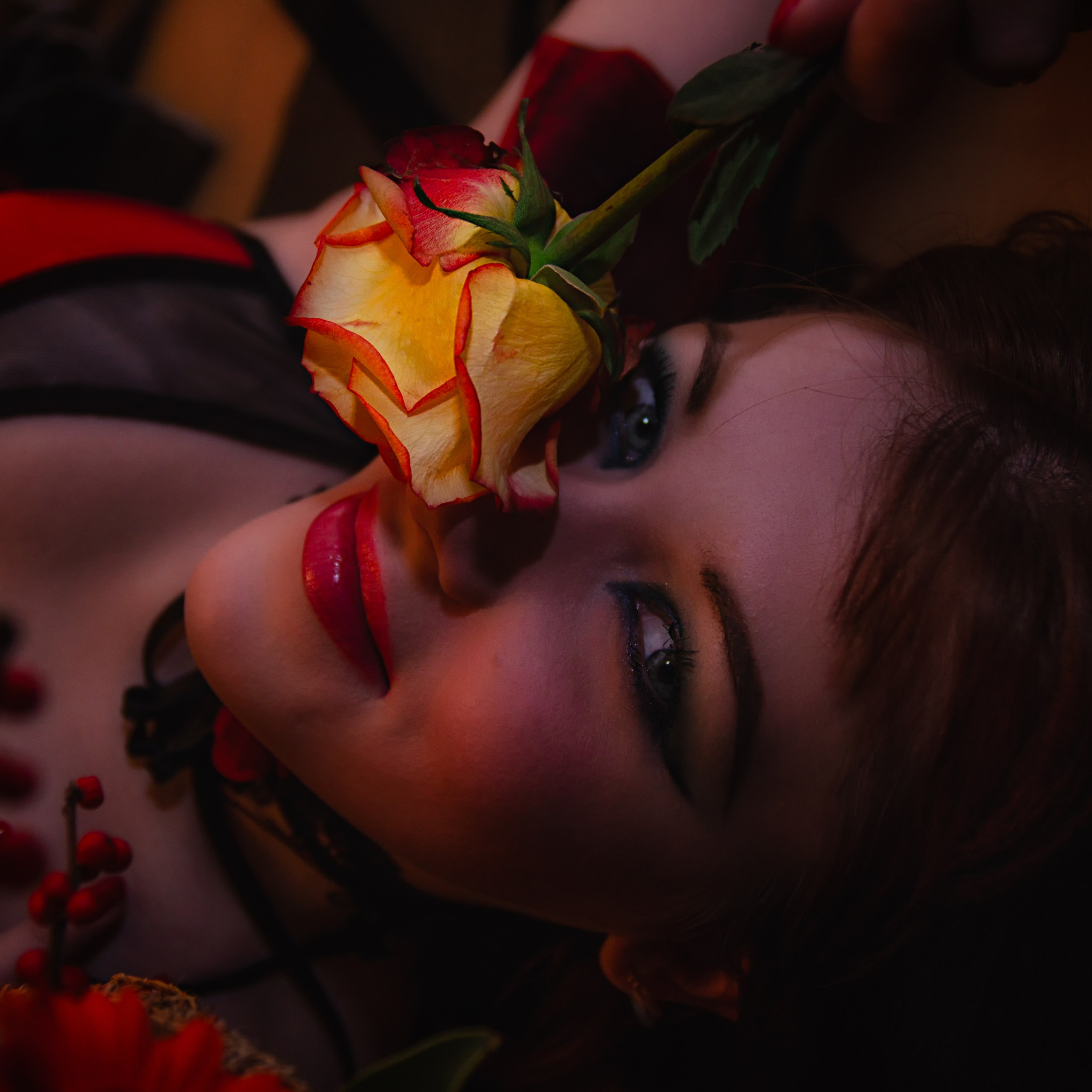 девушка с ярким макияжем и красными губами. Она держит жёлтую розу, которая подчёркивает её образ. Взгляд девушки направлен в камеру, создавая ощущение интриги и загадочности. Освещение подчёркивает её черты лица и создаёт эффектный контраст между светом и тенью.Заголовок: «Жёлтая роза: символ радости и дружбы»Ключевые слова: портрет, девушка с розами, жёлтая роза, романтика, красота, стиль, фотограф Сафронов Иван, Москва.