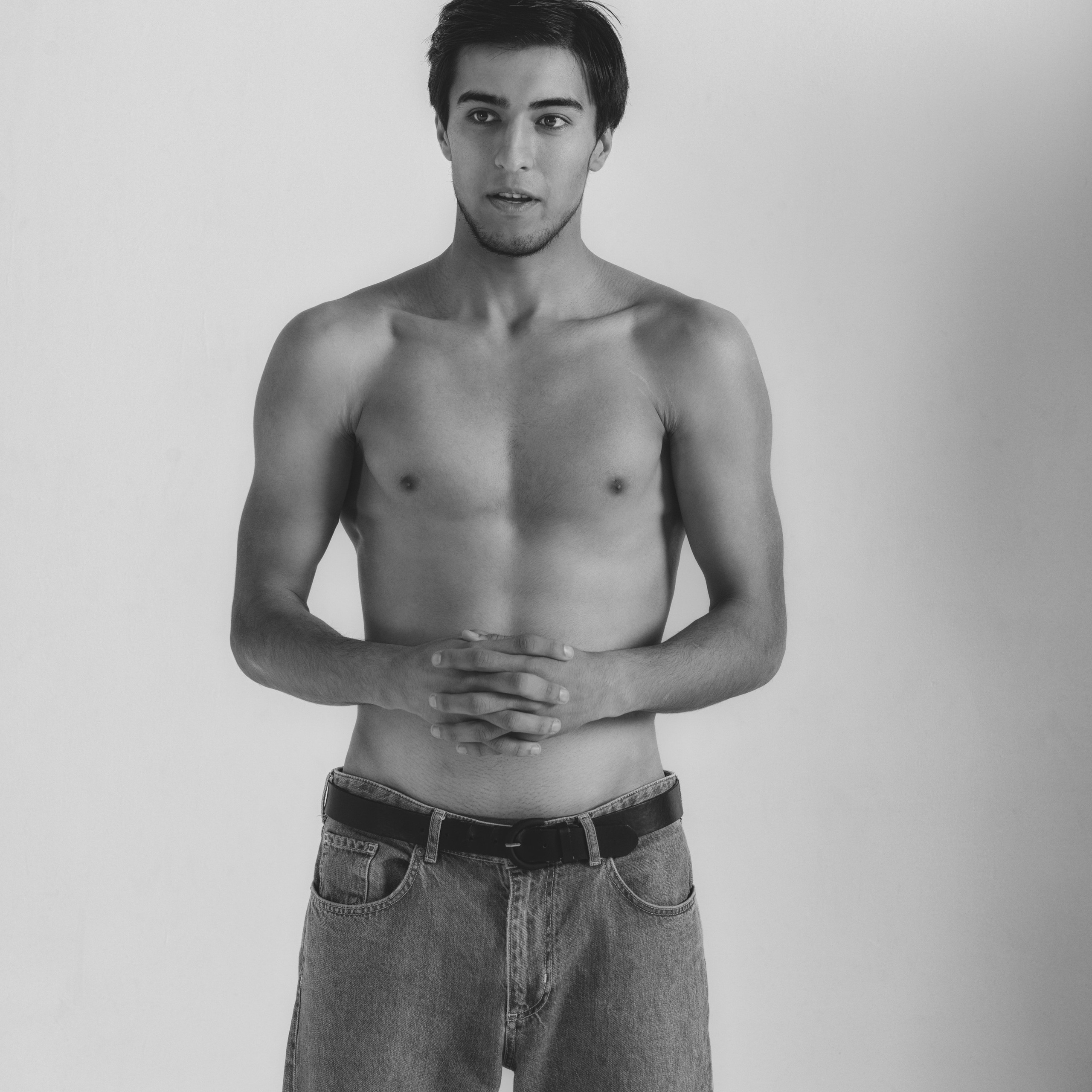 На изображении молодой человек стоит на фоне светлого фона, создавая минималистичный и стильный портрет. Его поза спокойная, руки сложены перед собой, что подчеркивает уверенность и естественность. Черно-белая гамма добавляет снимку художественности и акцентирует внимание на деталях.Заголовок: «Сила простоты: минималистичный портрет»Ключевые слова: портретный фотограф в Москве, фотограф Сафронов Иван, минимализм, черно-белая фотография, мужской портрет.