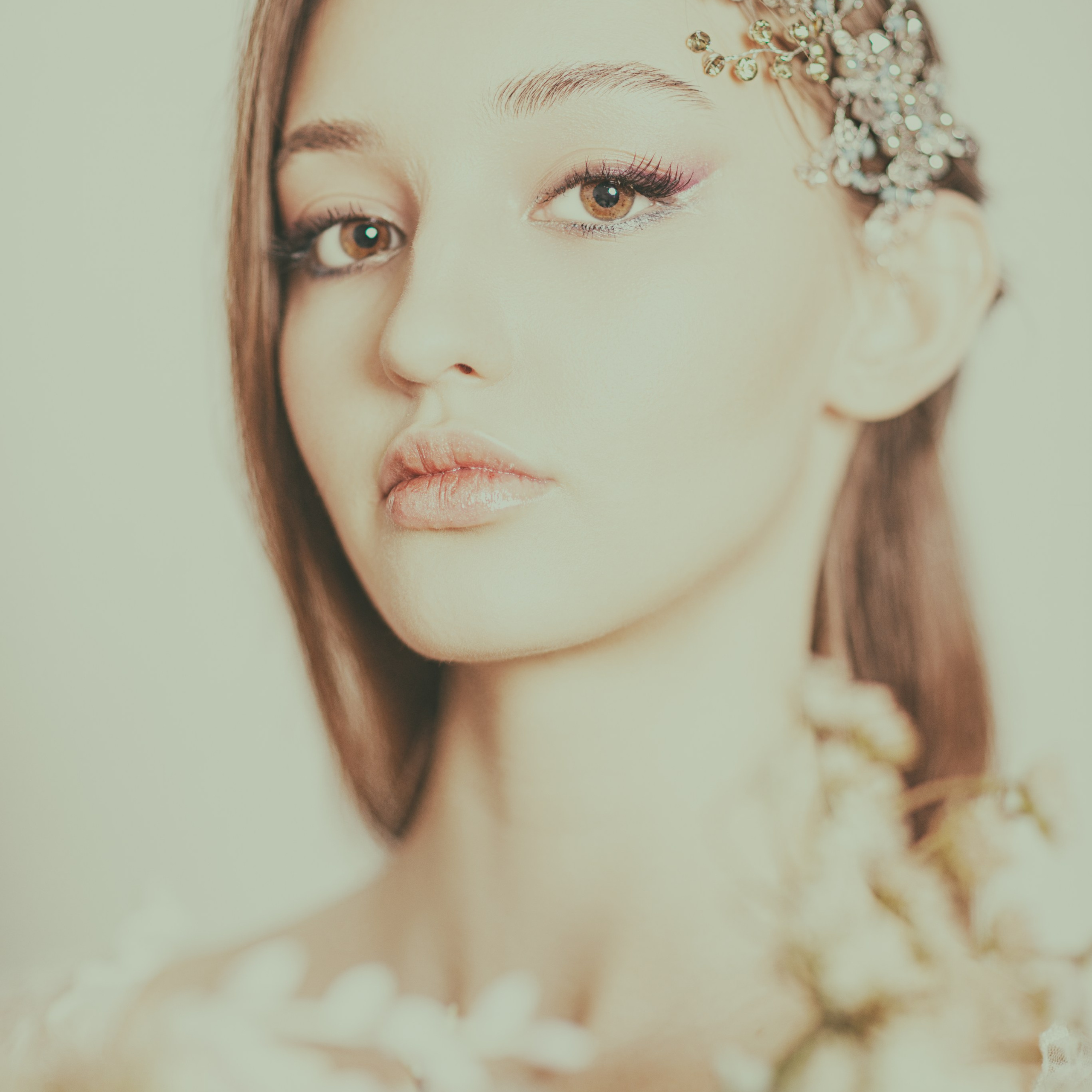 На портрете изображена молодая женщина с нежным макияжем и выразительным взглядом. Её волосы украшены изысканной повязкой с цветочным орнаментом, а в руках она держит букет цветов. Светлое освещение подчёркивает её черты лица и создаёт атмосферу утончённости и романтики.Заголовок:«Цветочная нежность: портрет с повязкой и цветами»Ключевые слова:портретный фотограф в Москве, фотограф Сафронов Иван.