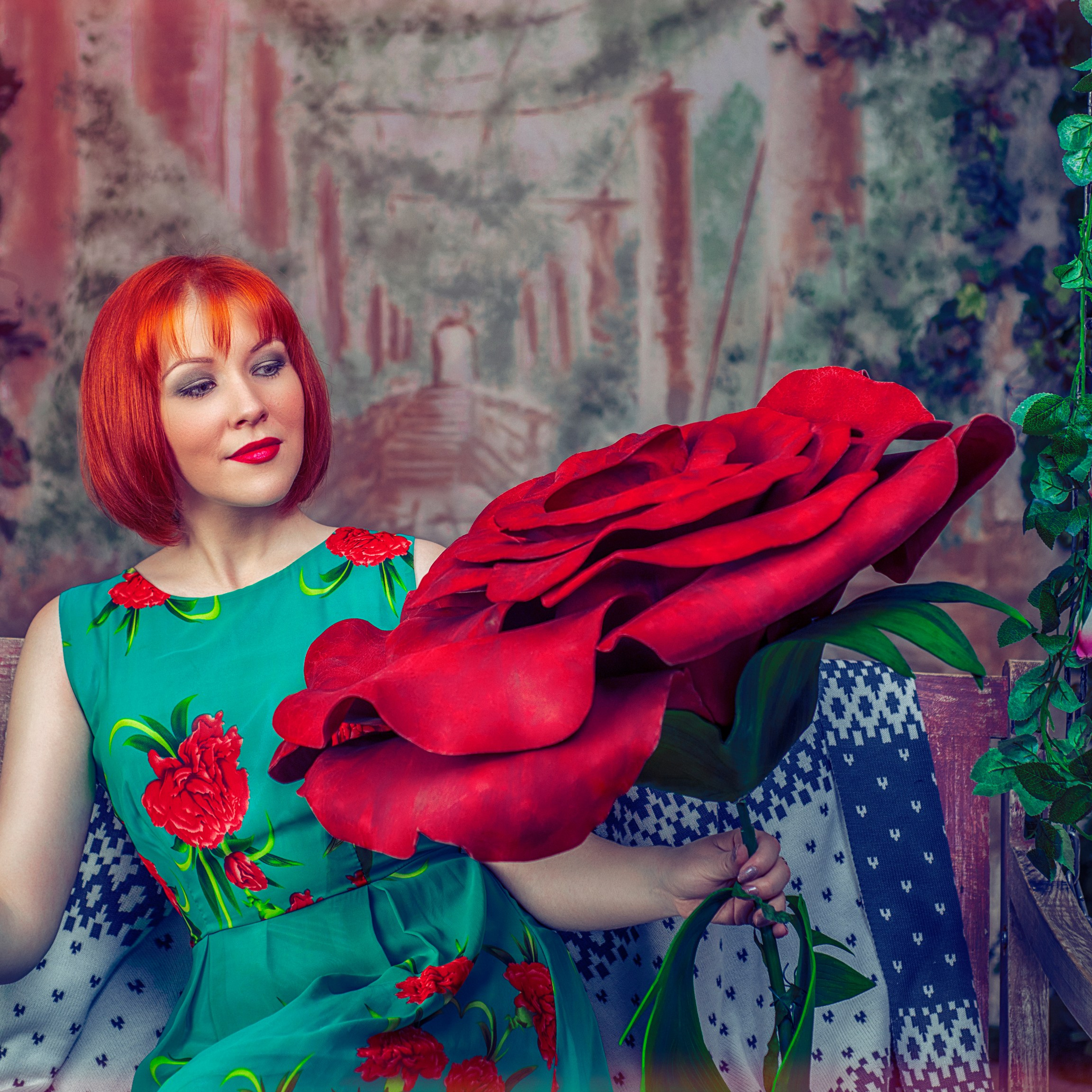 Рыжая девушка держит огромный цветок розы в руках