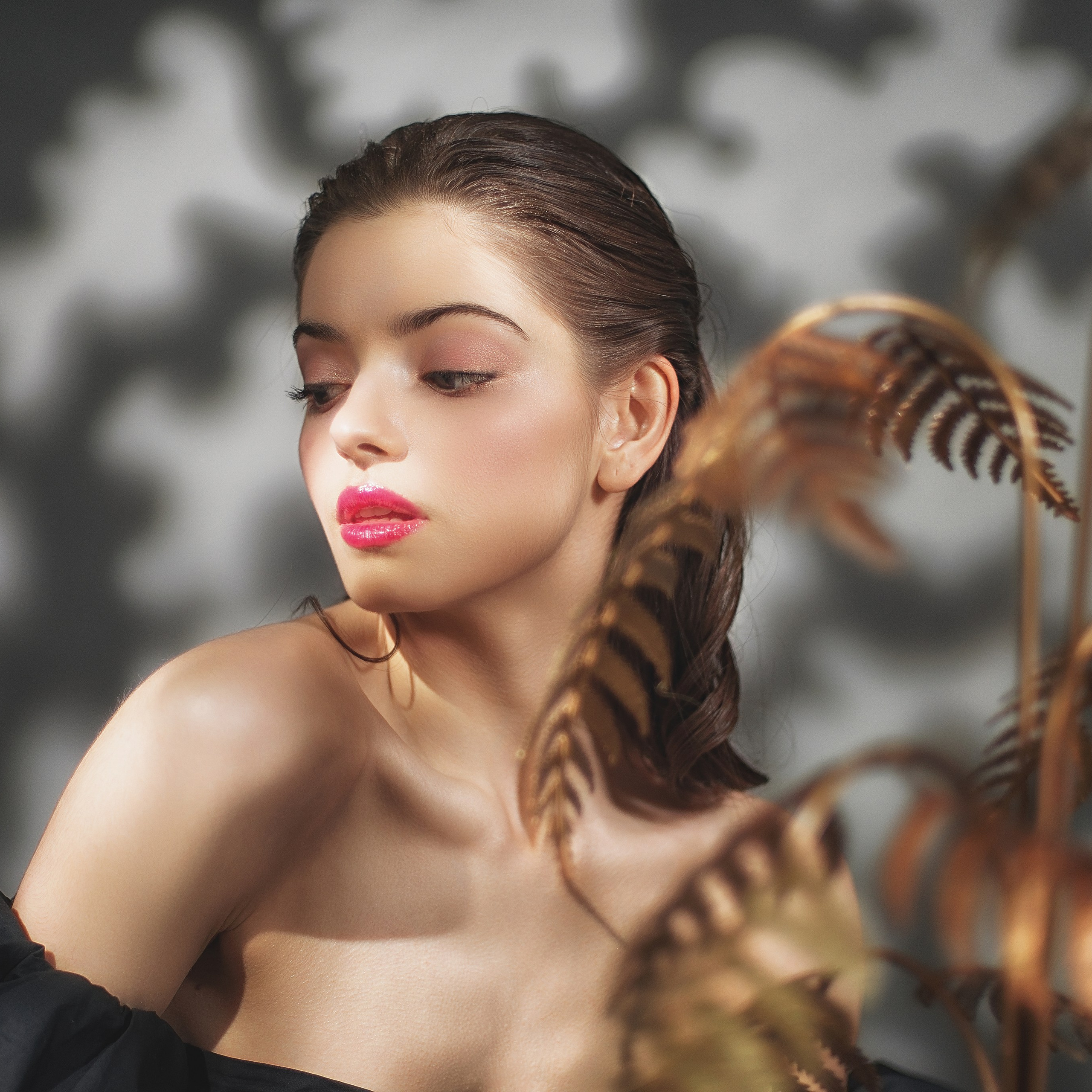 Девушка сидит в тени от растения