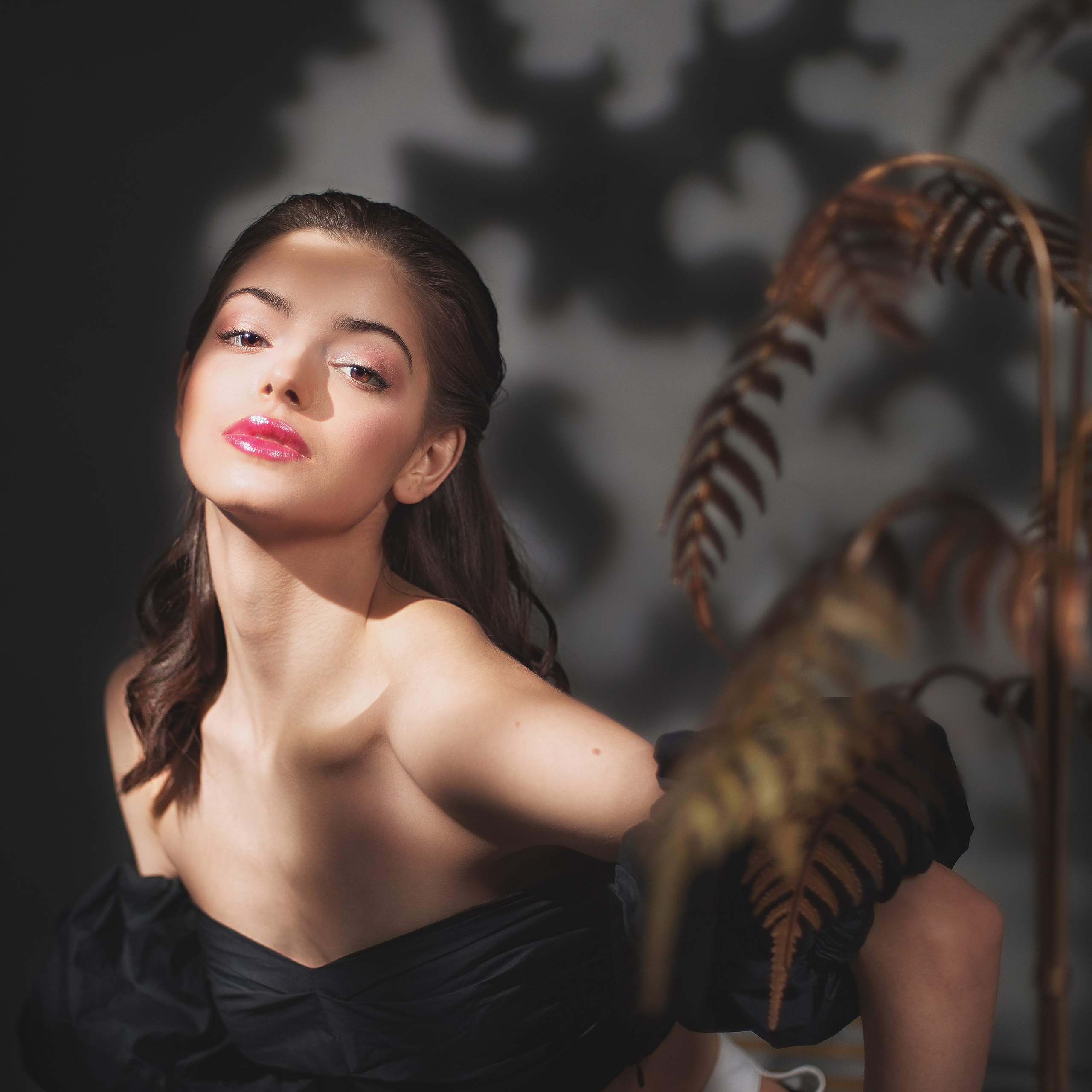 Девушка в тени веток показывает плечо