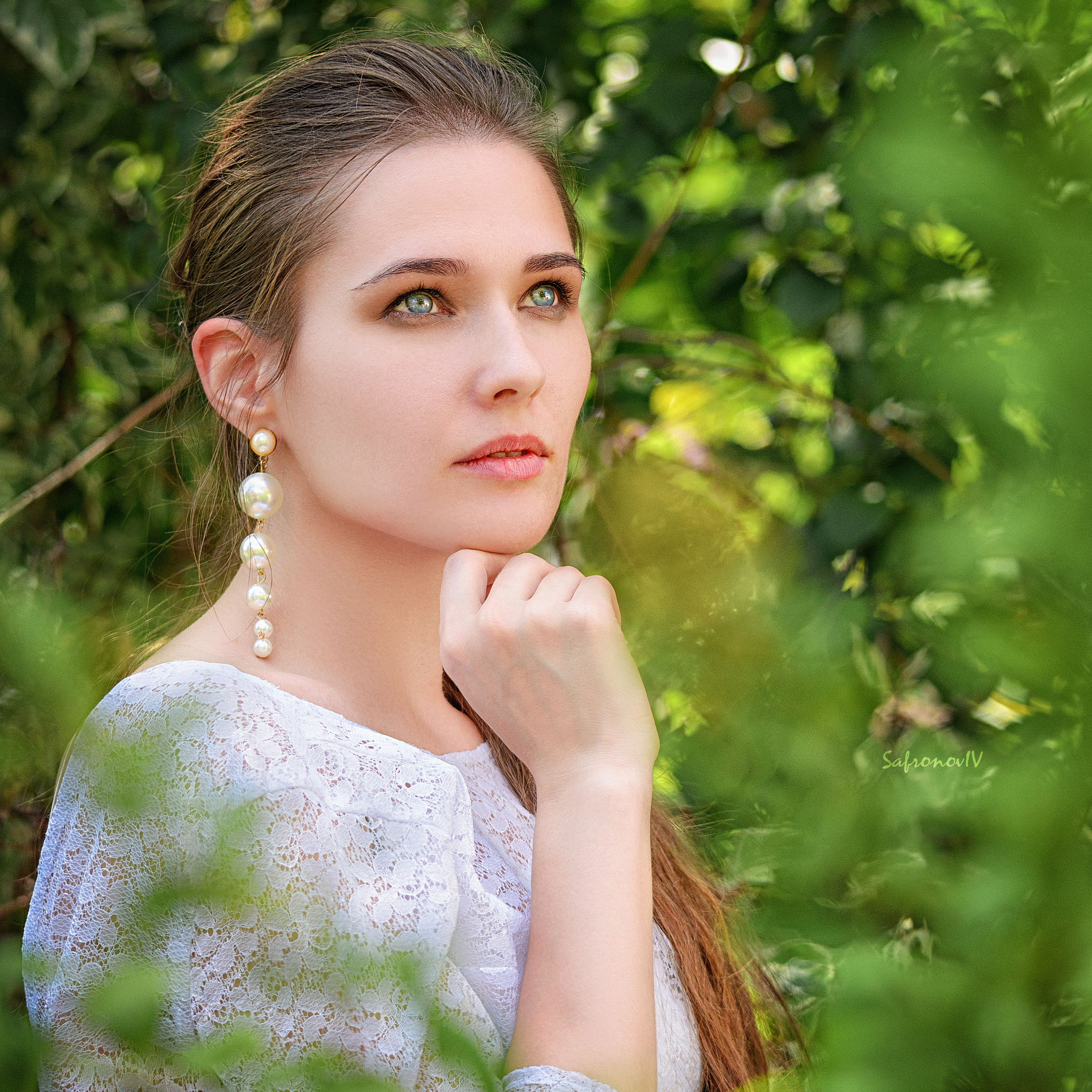 Девушка в белом платье за листвой