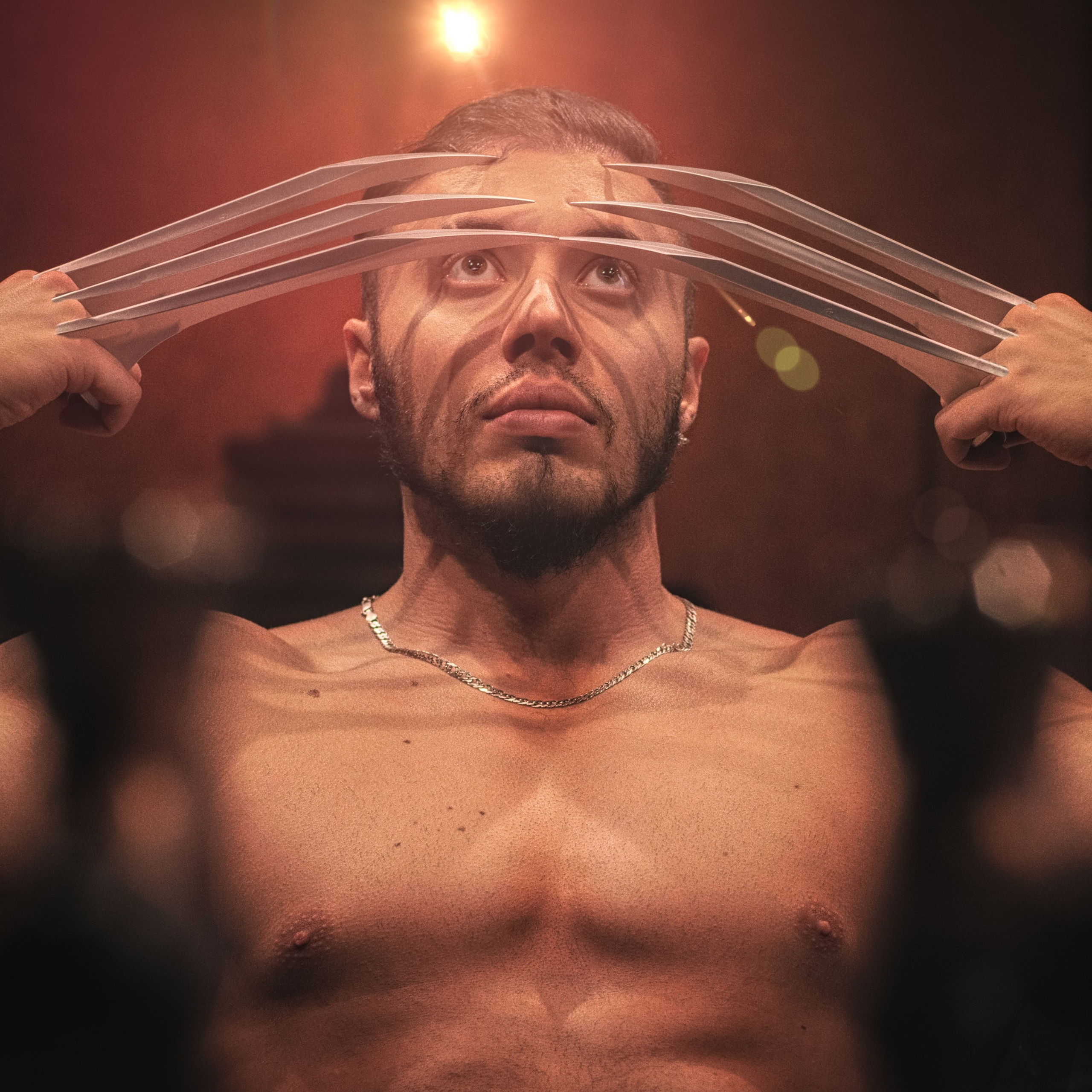 мужчина с серьёзным выражением лица, держащий металлические когти, напоминающие культовые когти Росомахи из серии «Люди Икс». Его взгляд устремлён вверх, создавая ощущение силы и решимости. Освещение подчёркивает его мускулистое телосложение и добавляет драматичности сцене.Заголовок: «Сила и решимость: портрет героя»Ключевые слова: портрет, Росомаха, когти, супергерой, сила, решимость, фотограф Сафронов Иван, Москва.