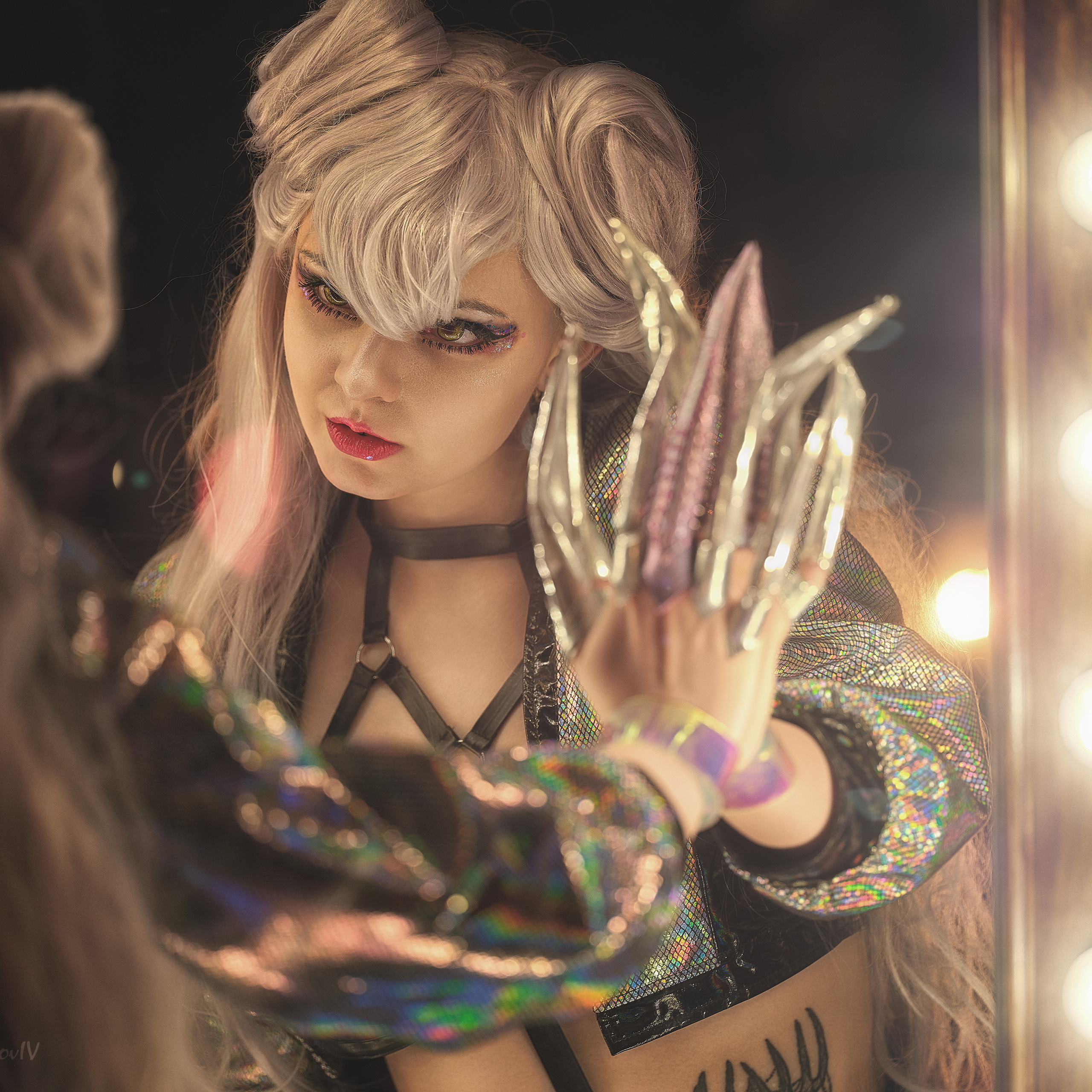 Девушка с длинным ногтями и парике смотрит на себя в зеркале