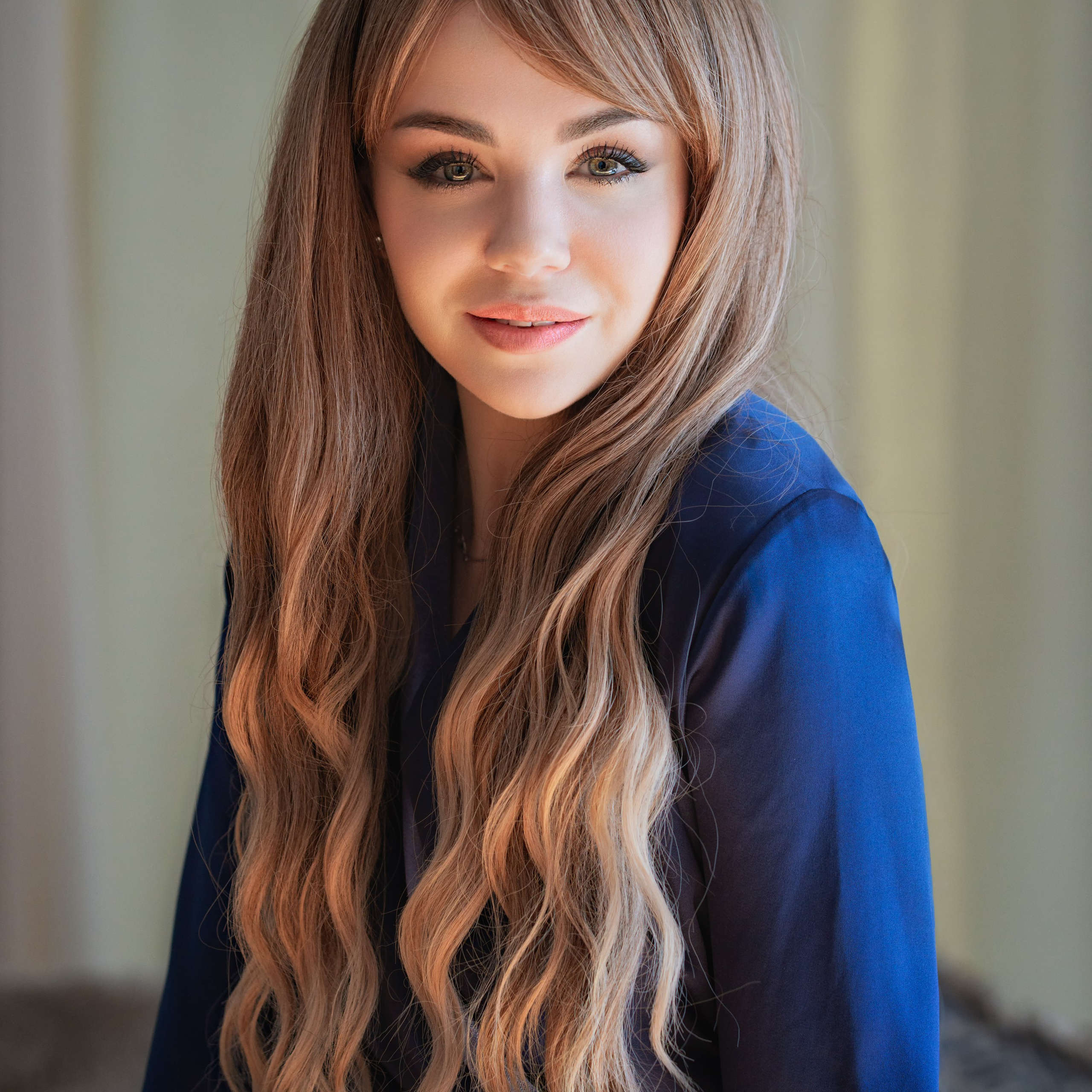 На изображении изображена молодая женщина с длинными волнистыми волосами, одетая в элегантный синий наряд. Её взгляд направлен прямо в камеру, создавая ощущение уверенности и спокойствия. Фон выполнен в светлых тонах, что подчёркивает мягкость и естественность образа. Освещение мягкое, подчёркивающее черты лица и текстуру волос.Заголовок: «Элегантность в каждом движении»Ключевые слова: портретный фотограф в Москве, фотограф Сафронов Иван, портретная фотография, женский портрет, синий наряд, мягкие волосы, естественное освещение.