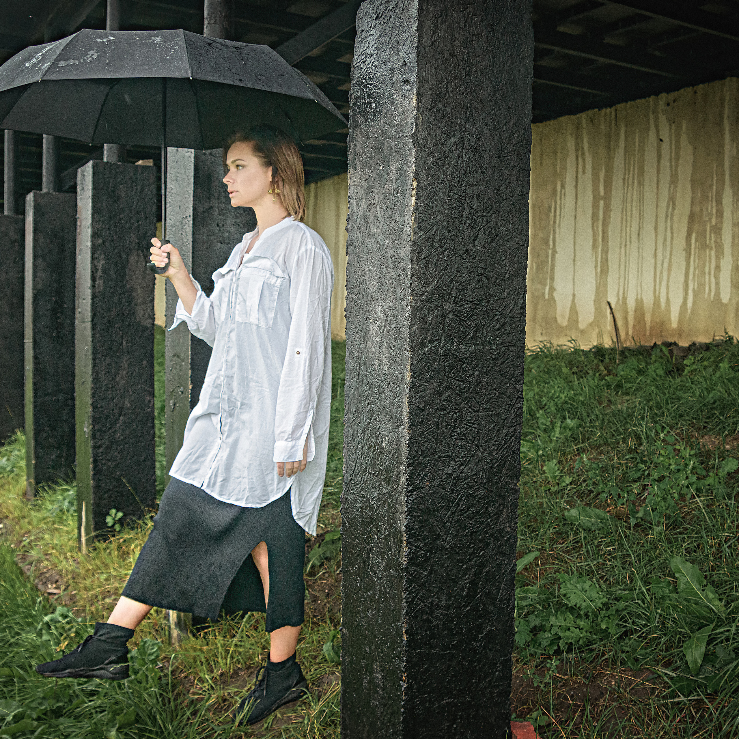 Женщина с зонтиком в белой длинной рубашке делает шаг вперед