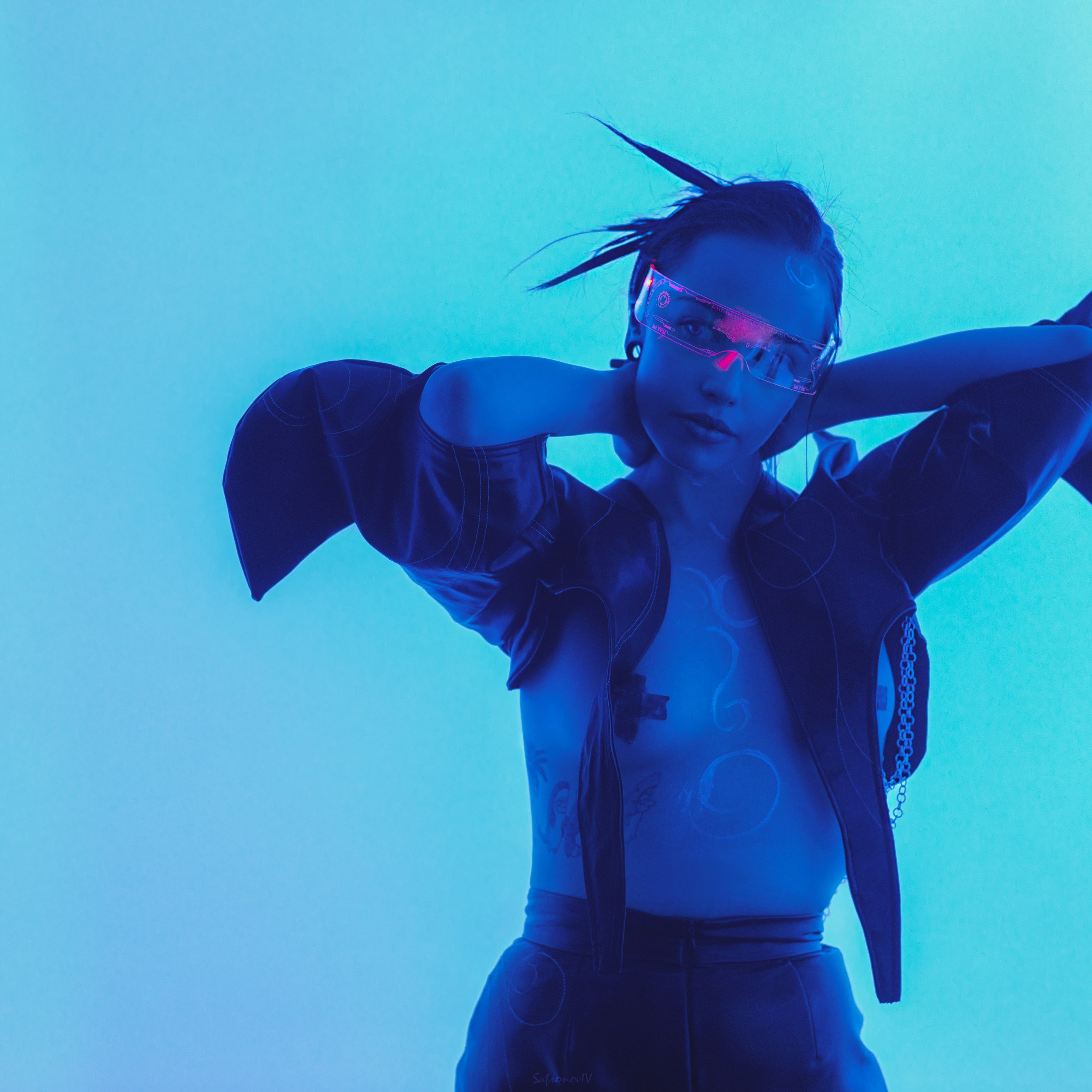 Девушка с открытой грудью держит руки за головй