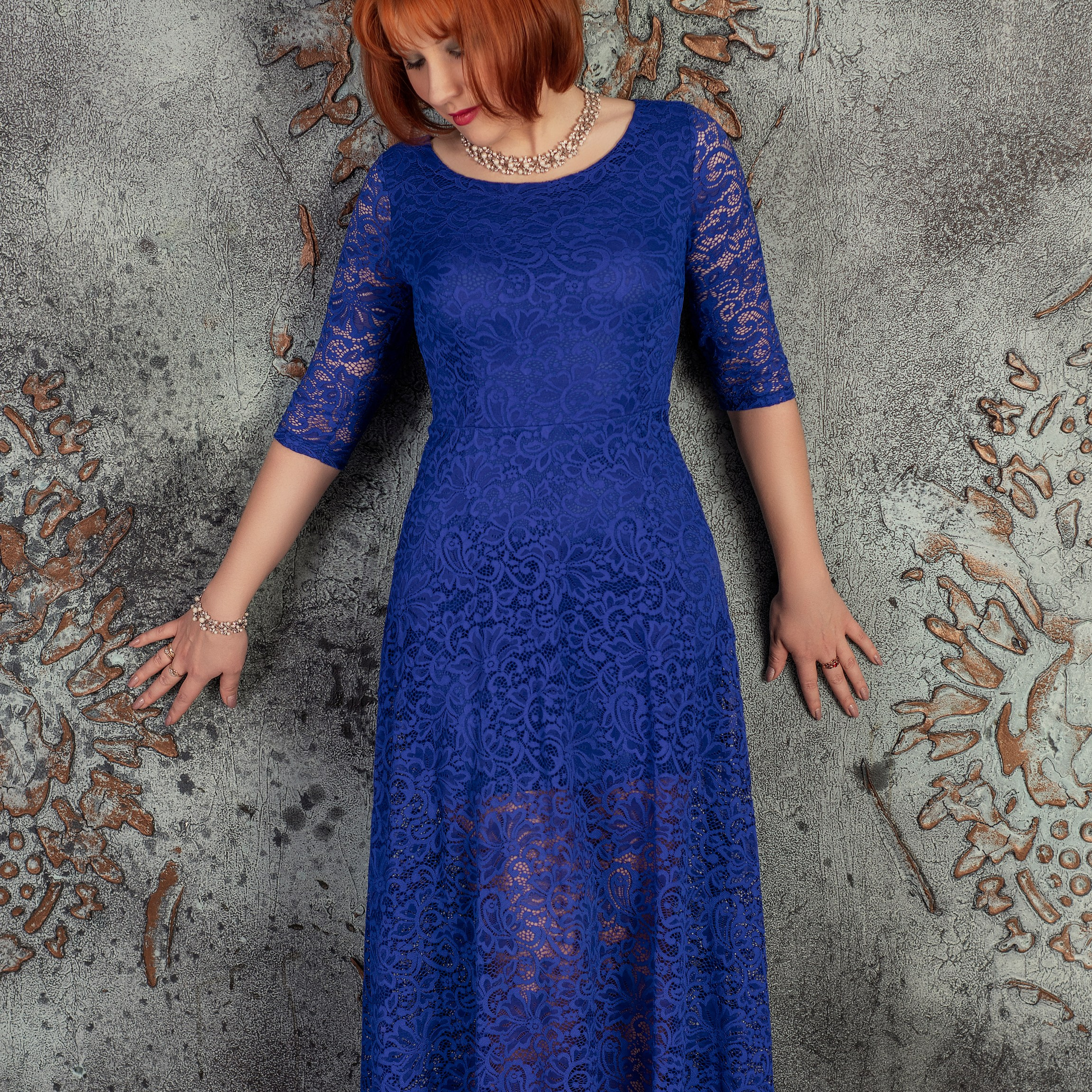 Девушка в синем платье у стены