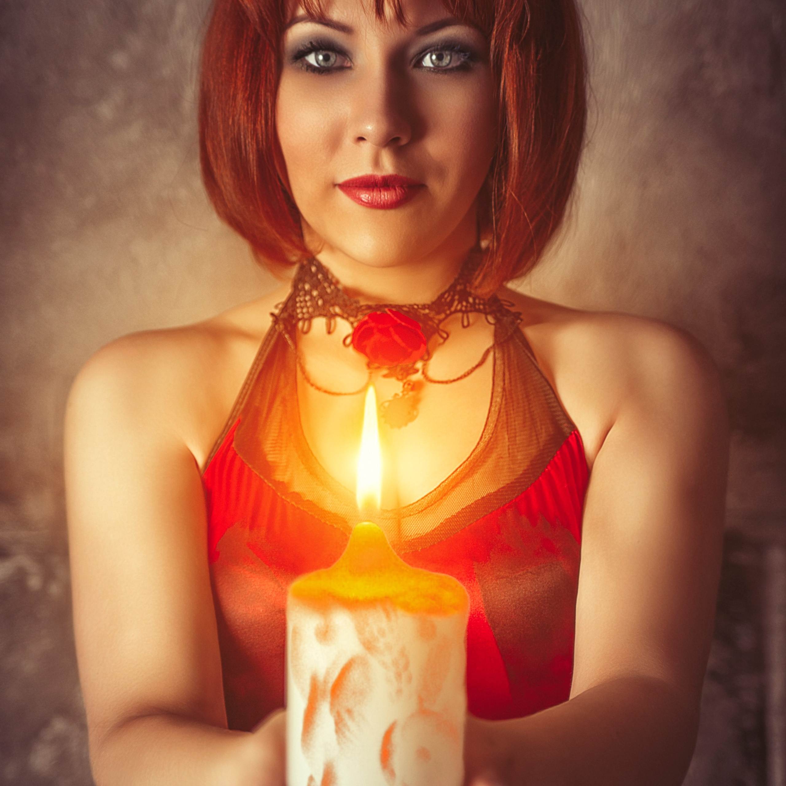 Девушка в красном платье держит в руках огромную свечу
