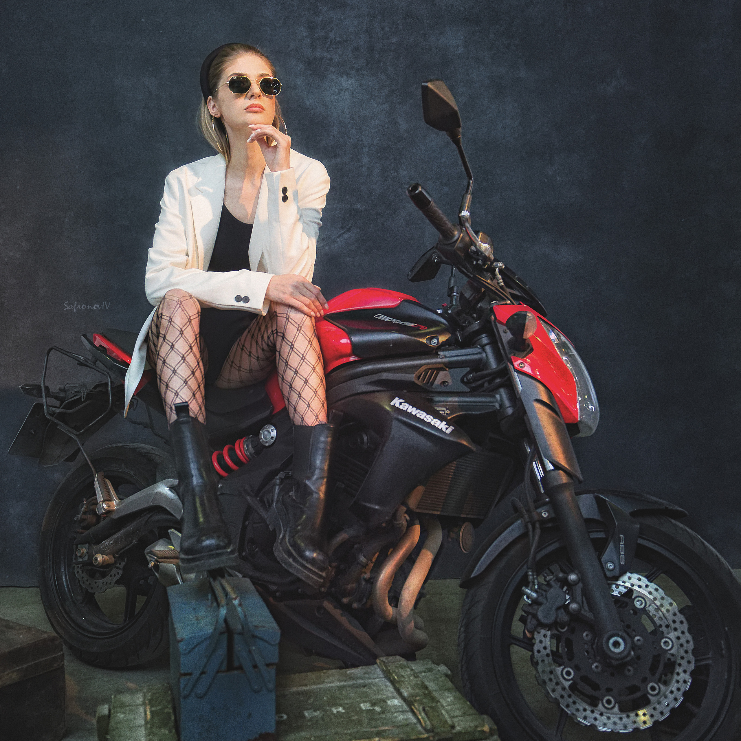 Девушка в очках сидит на красном байке. Внизу военные ящики