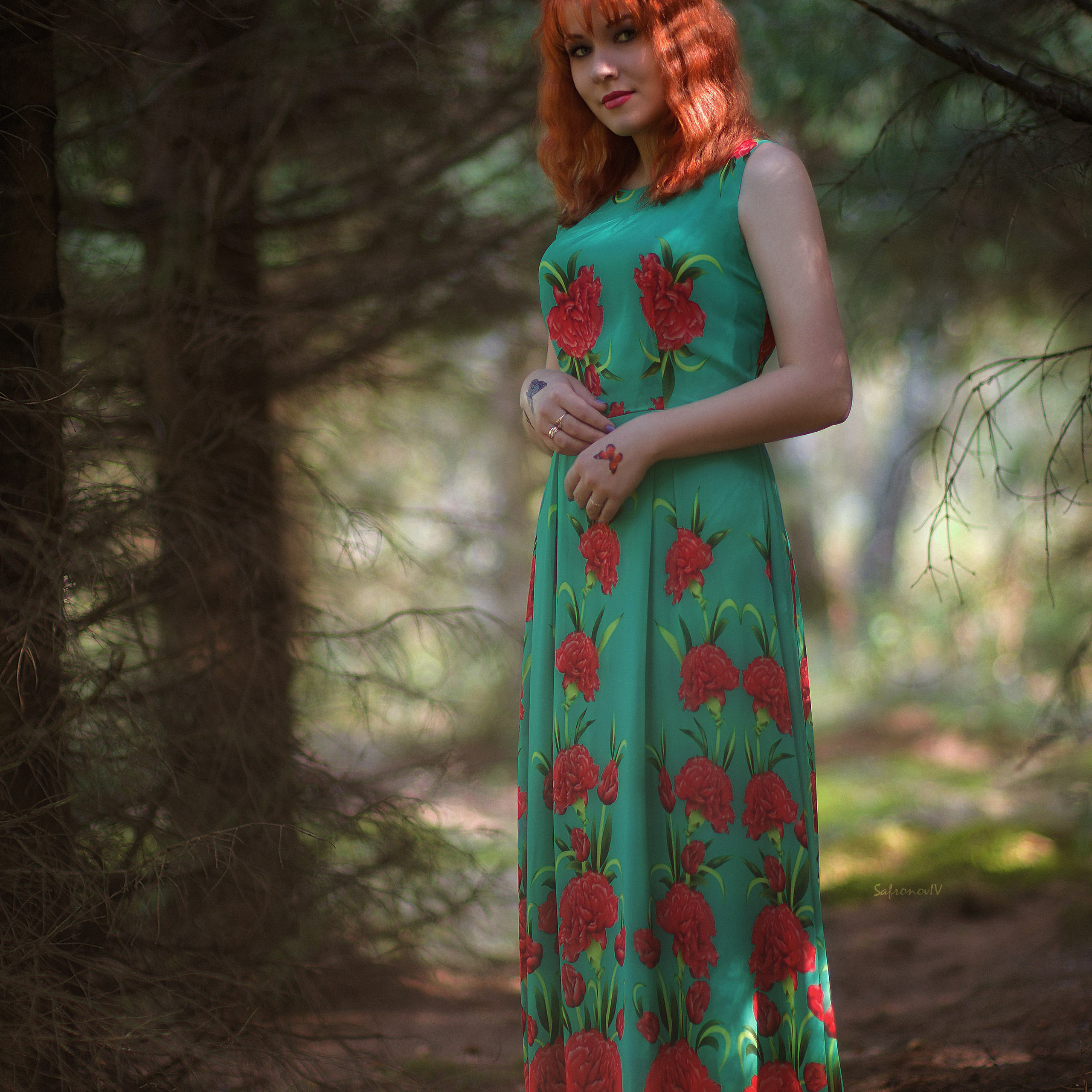 Рыжая девушка в зеленом платье летом в лесу
