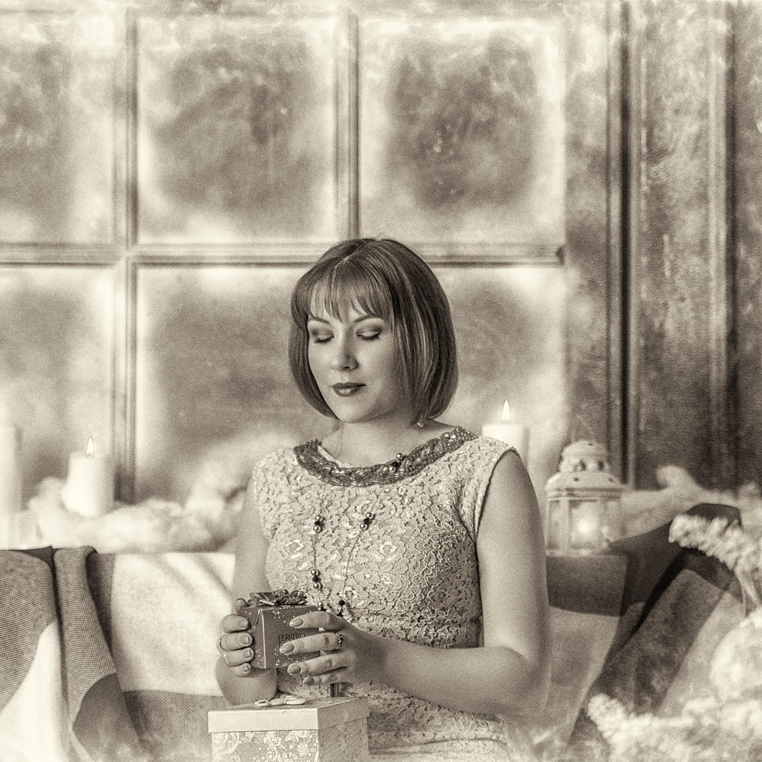 молодая женщина, сидящая у окна. Она держит в руках чашку с горячим напитком, возможно, чаем или кофе. Её взгляд направлен вниз, создавая атмосферу уюта и спокойствия. На заднем плане видны большие окна, через которые проникает мягкий свет, а также элементы интерьера, такие как плед и декоративные детали. Женщина одета в светлое платье с кружевным узором, что добавляет образу нежности и элегантности.Заголовок: «Момент уюта и спокойствия»Ключевые слова: портрет, уют, зима, окно, чай, женщина, интерьер, спокойствие, фотограф Сафронов Иван, Москва.