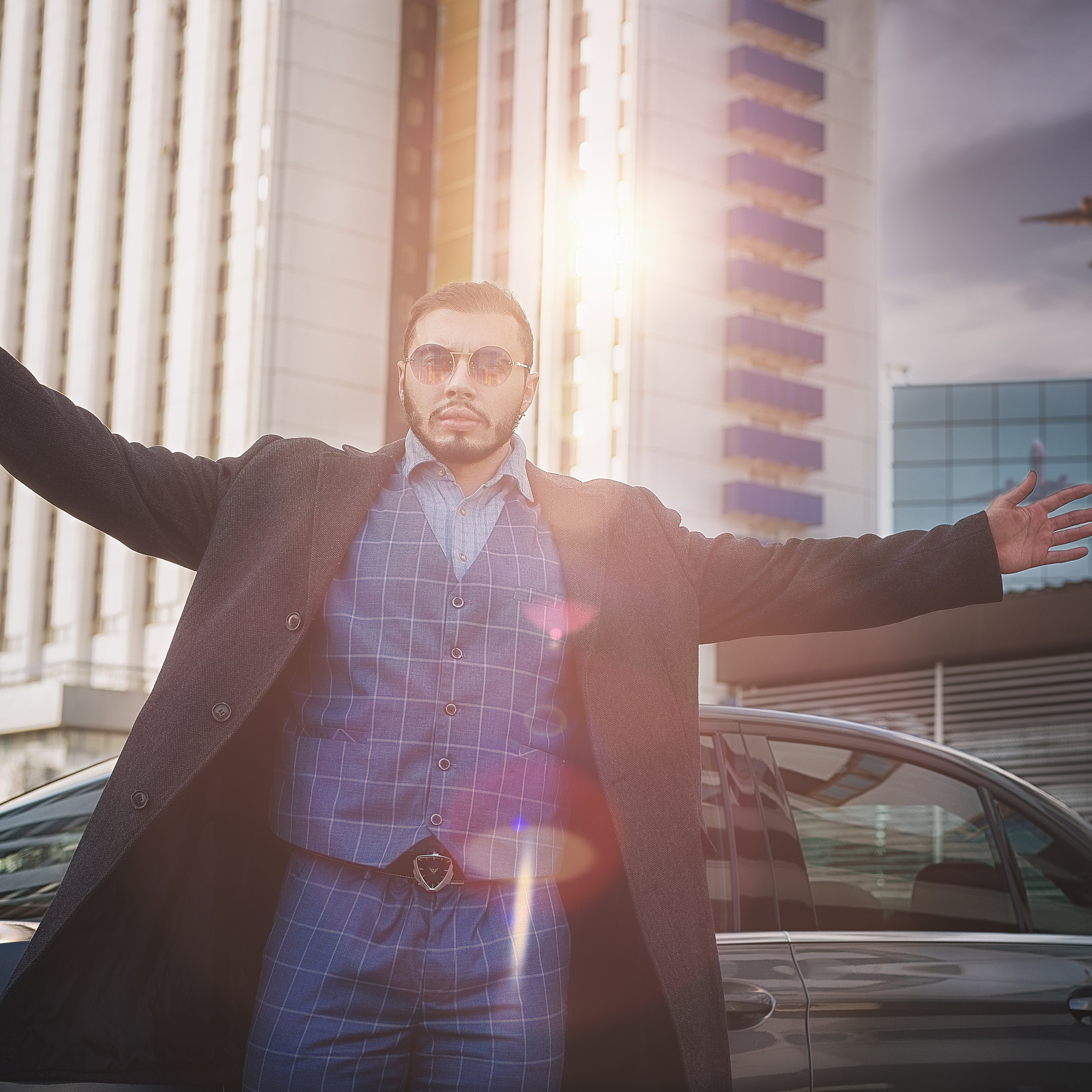 Бизнесмен в пальто на фоне машины и небоскреба