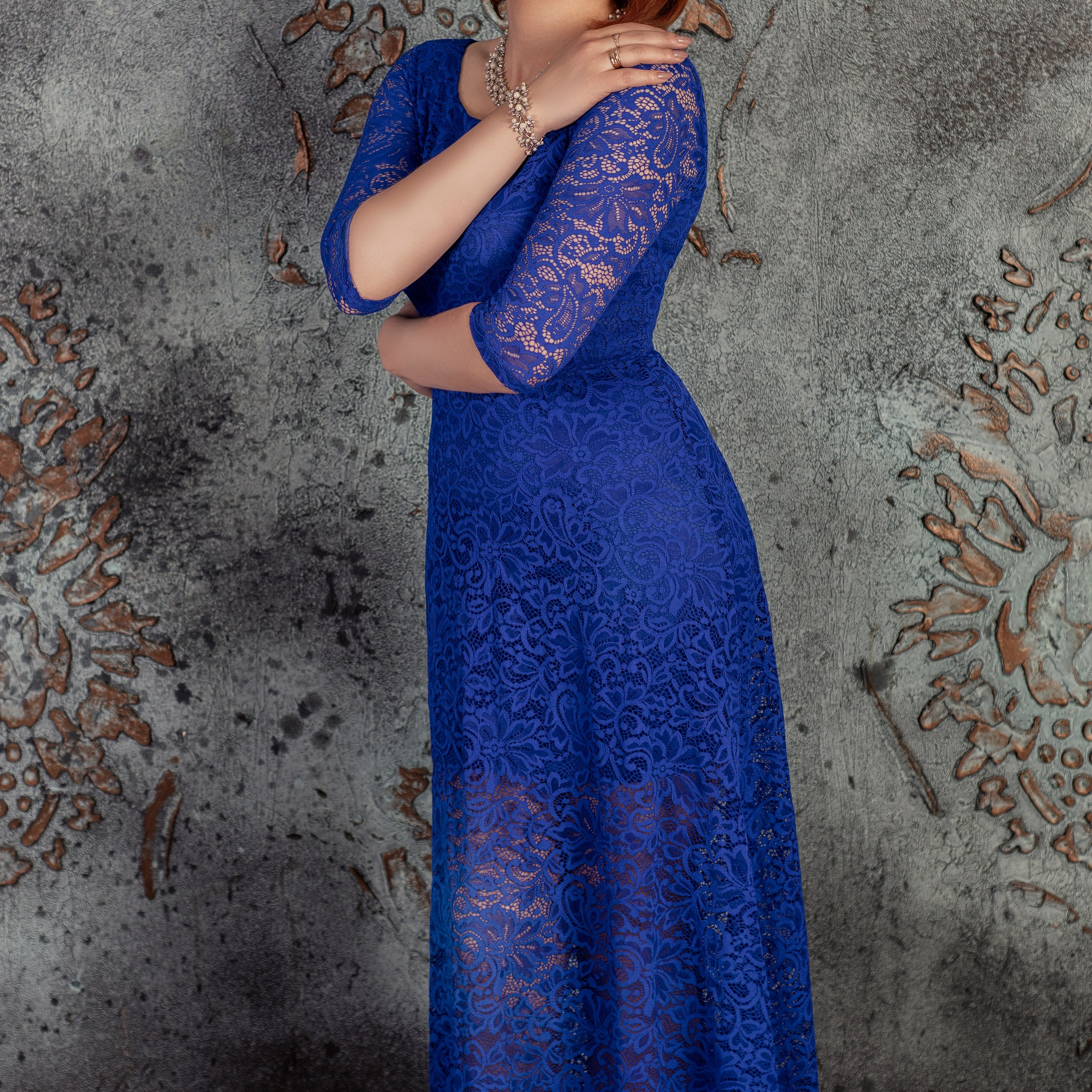 Девушка в синем платье обнимает себя