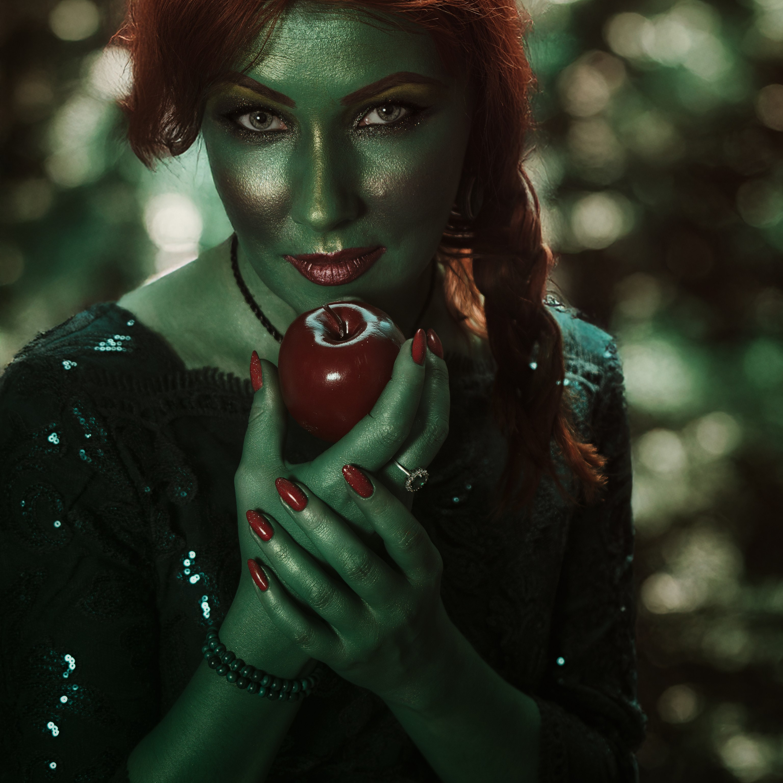 Зеленая девушка держит яблоко