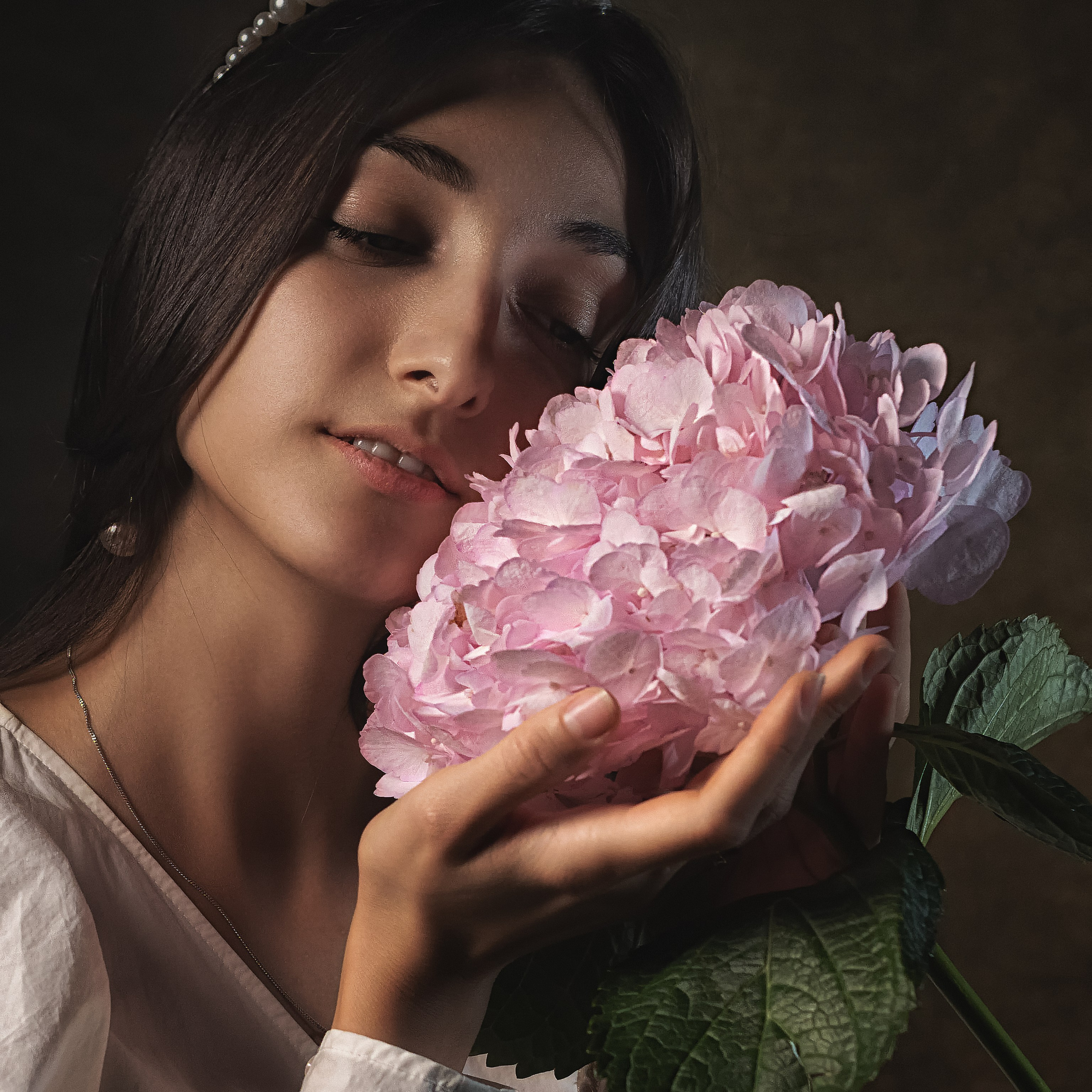 Девушка нежно прижимает цветок к щеке