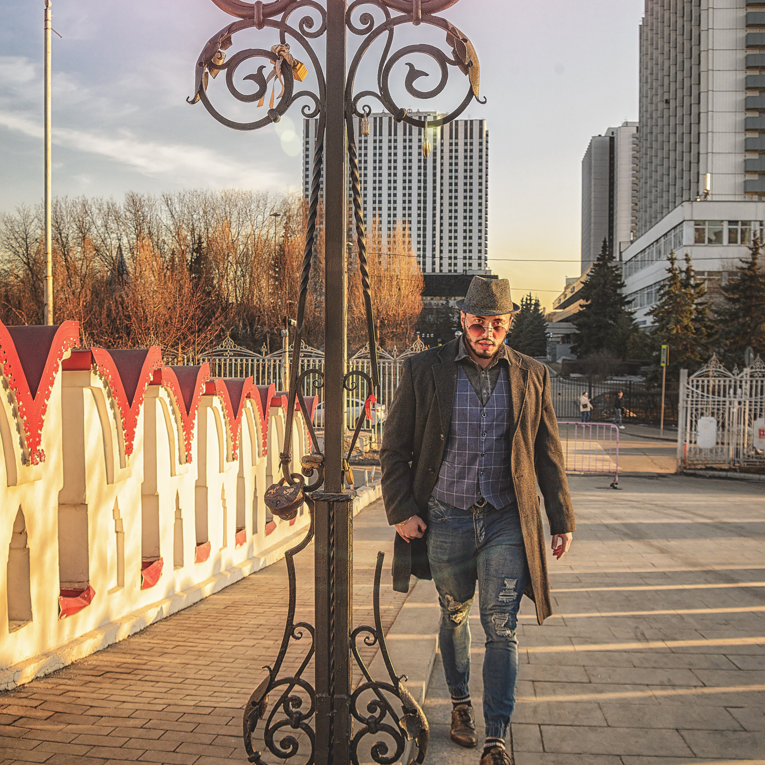 Мужчина в шляпе и пальто прогуливается по мосту