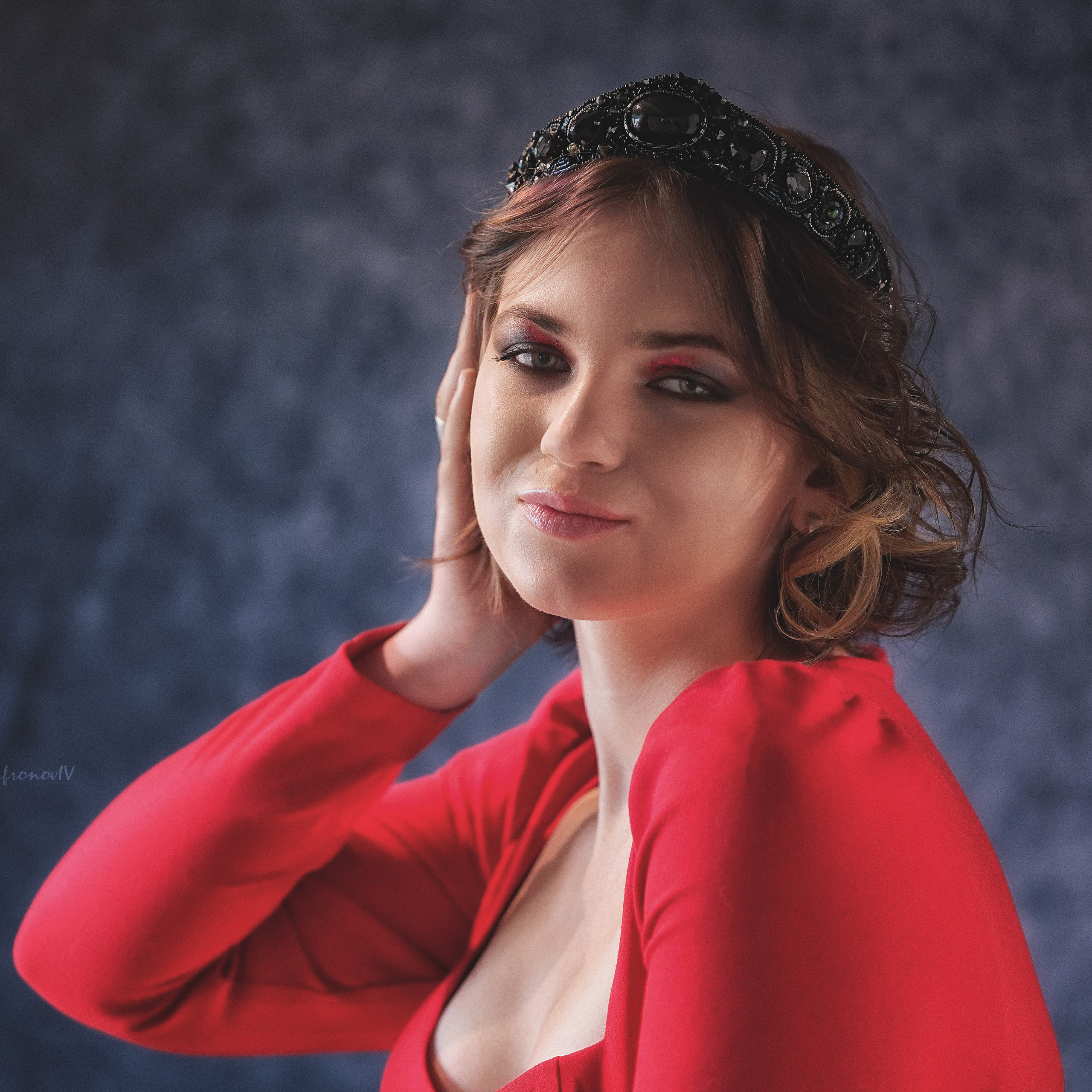 Девушка в красном платье приложила руку к лицу