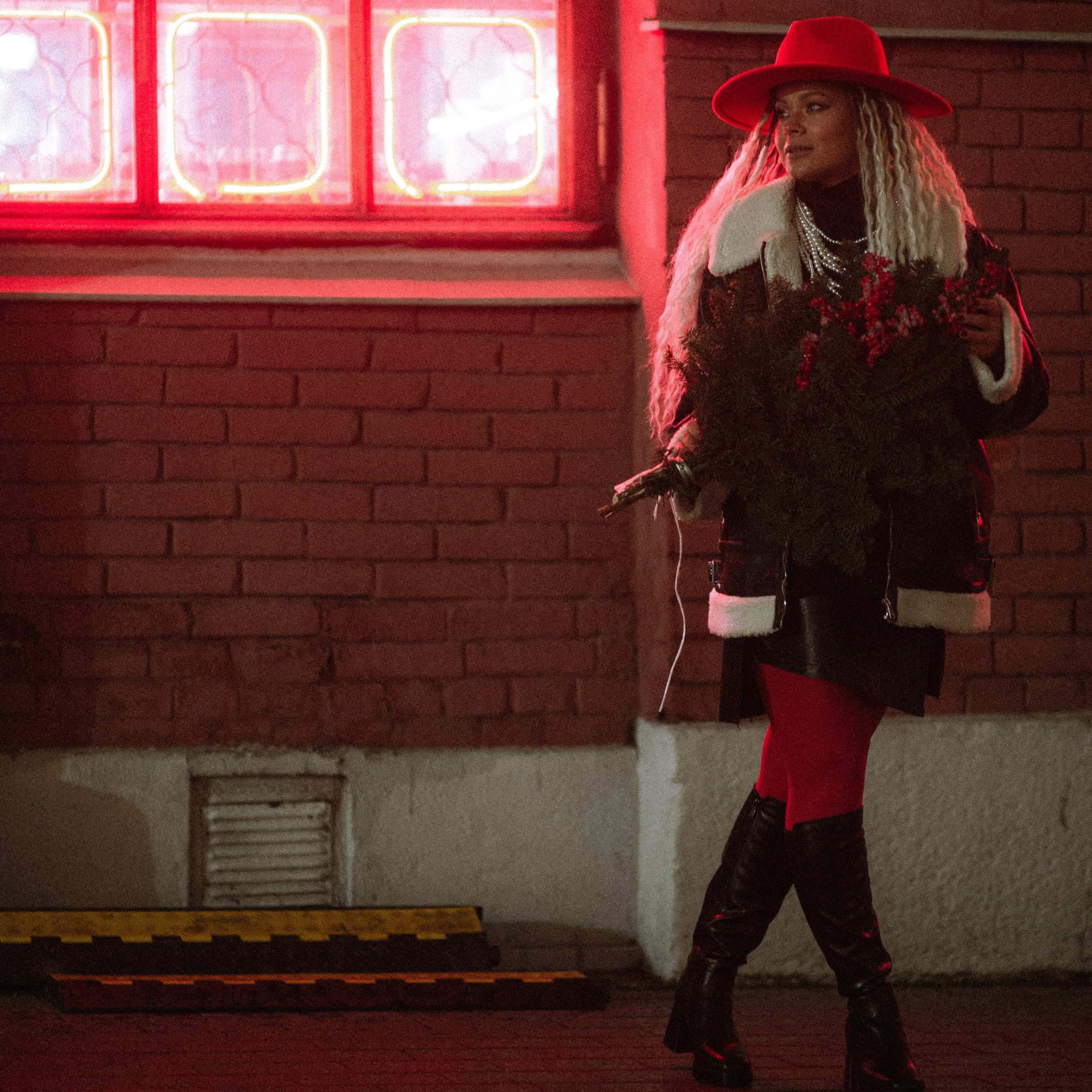 Девушка роскошно стоит на улиц в красном цвете фонарей