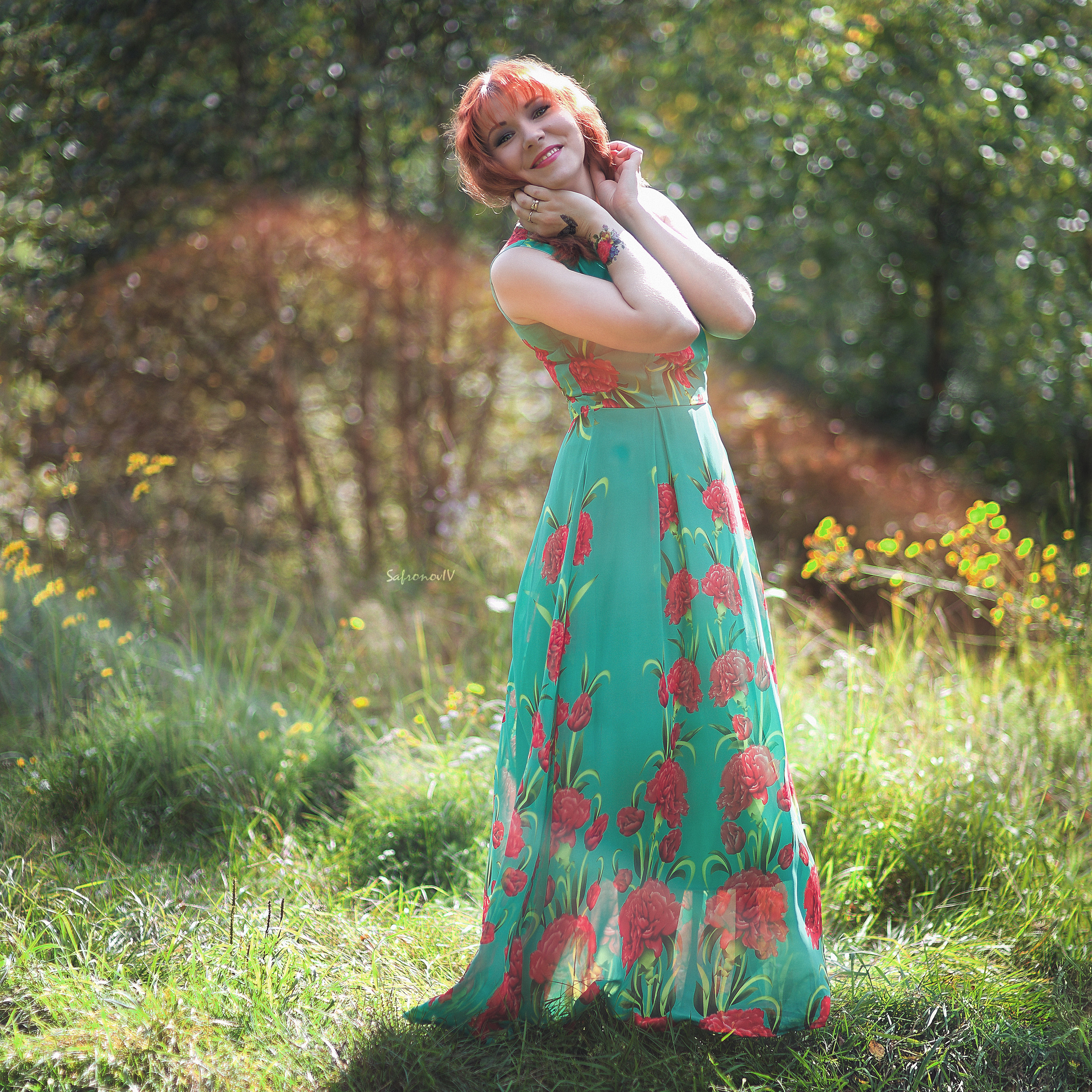 Счастливая девушка в платье на поляне в солнечных лучах