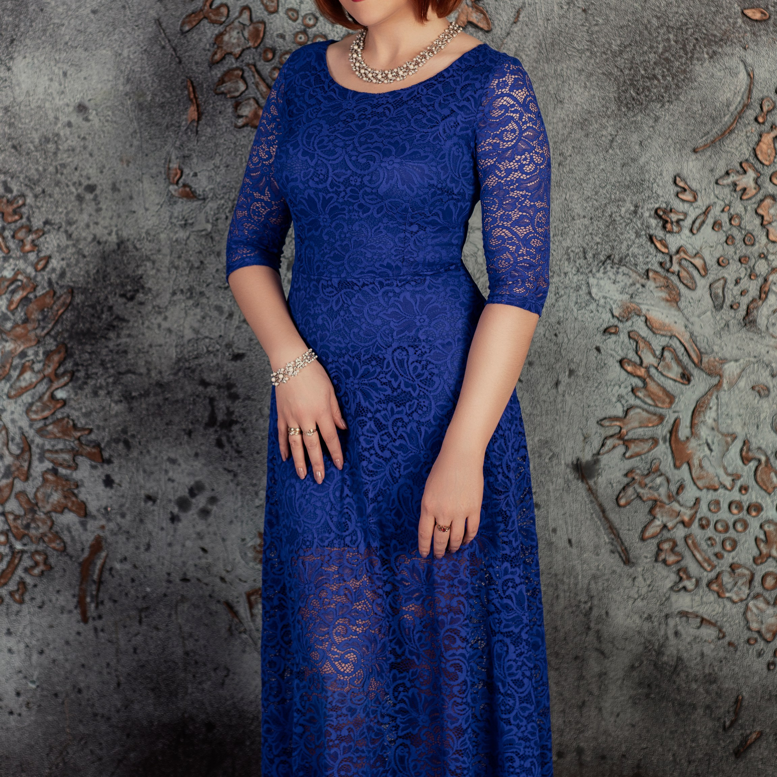 Рыжая девушка в синем платье возле красивой стены