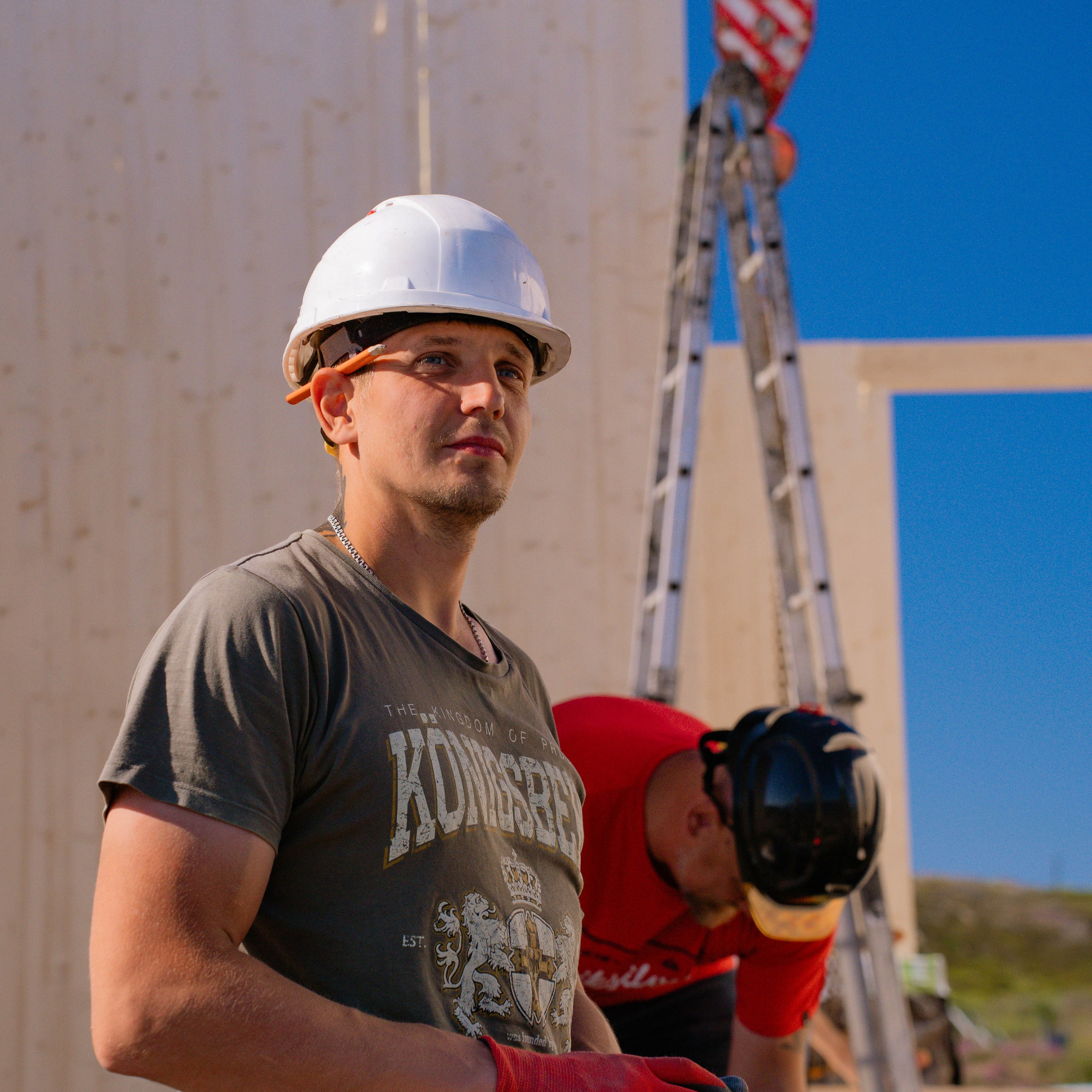 работник смотрит с сторону на фоне стройки