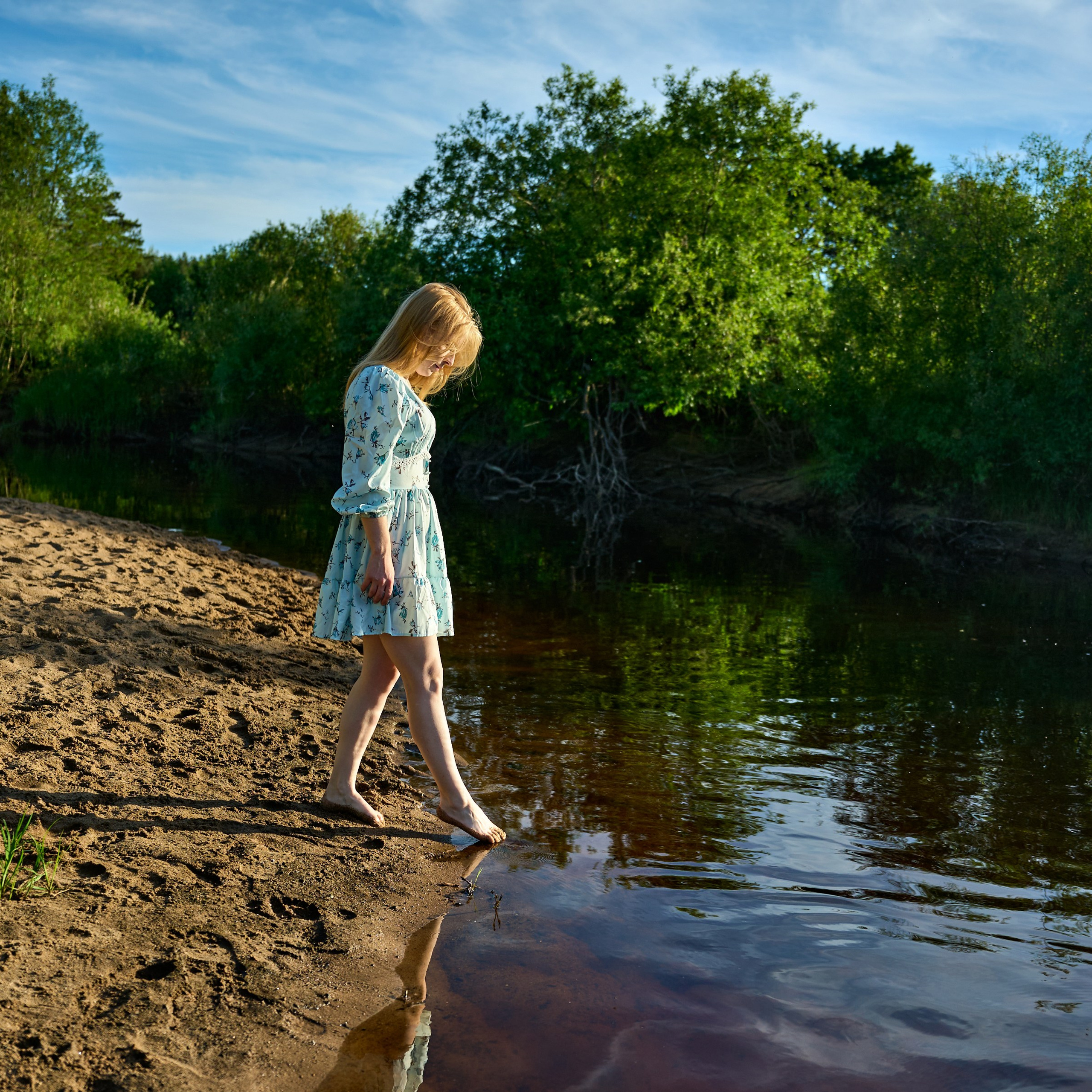 Идёт по песчаному берегу реки, смотрит на воду