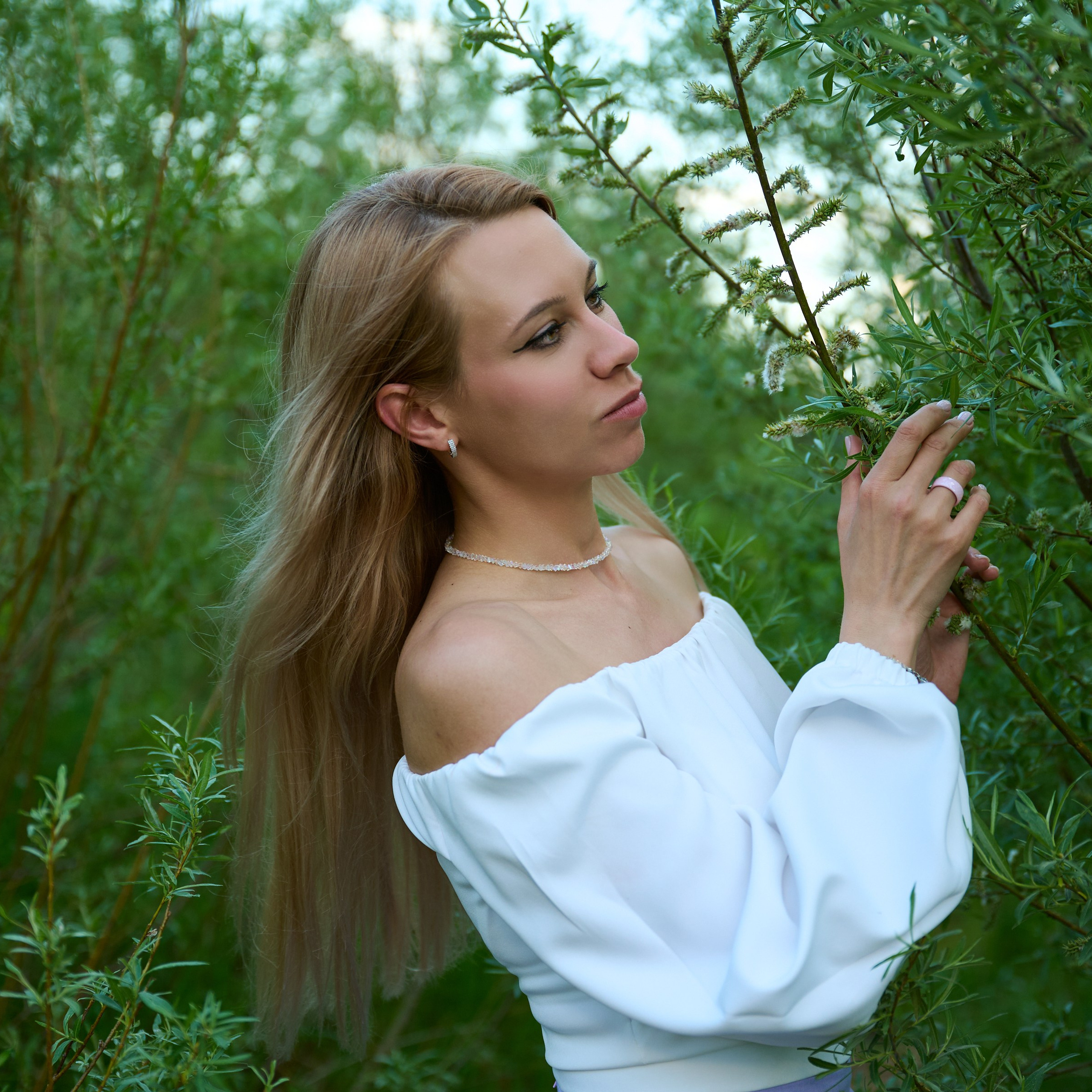 Крупный план лица среди зелёных кустов, лиловая юбка