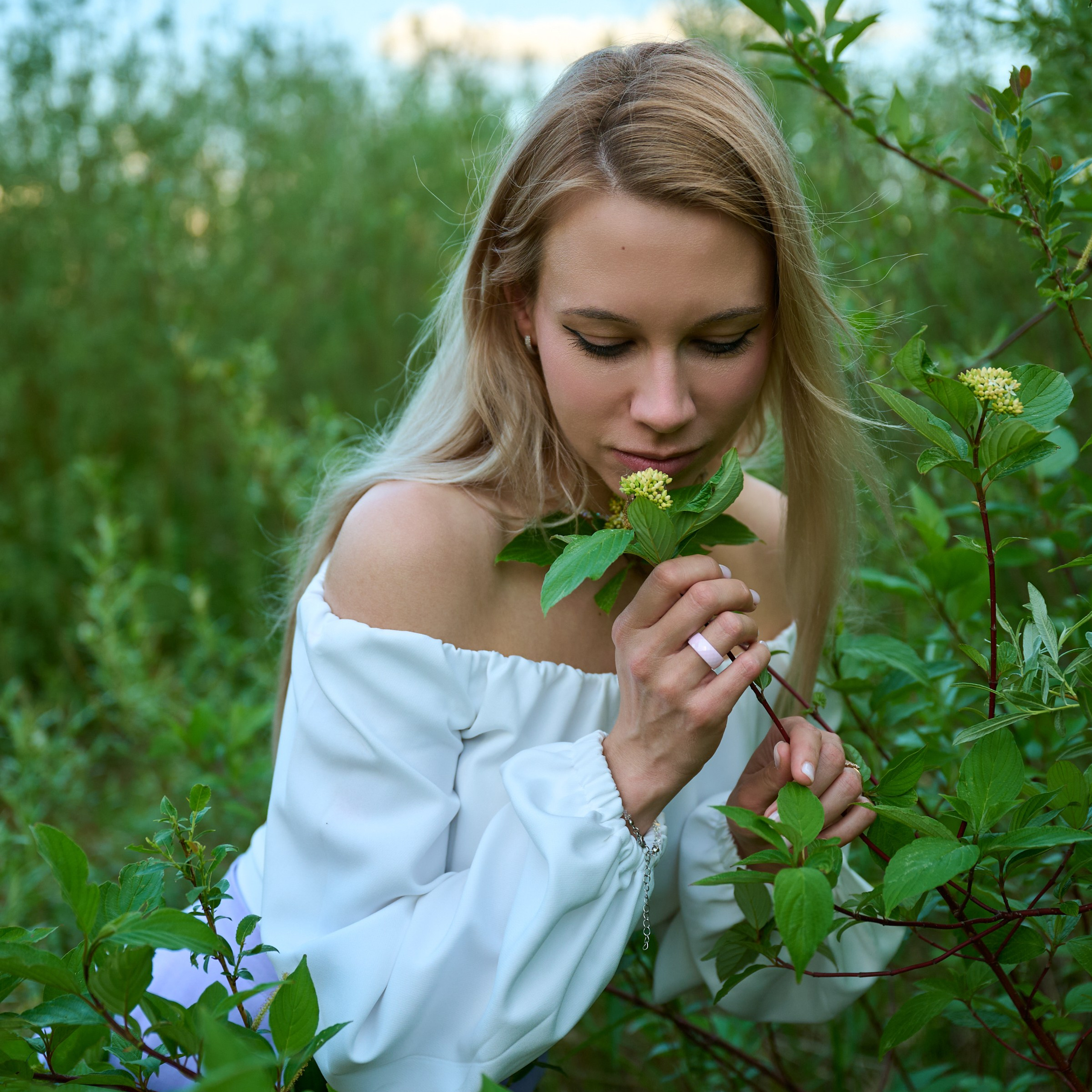 Нюхает полевой цветок, крупный план, белая блуза