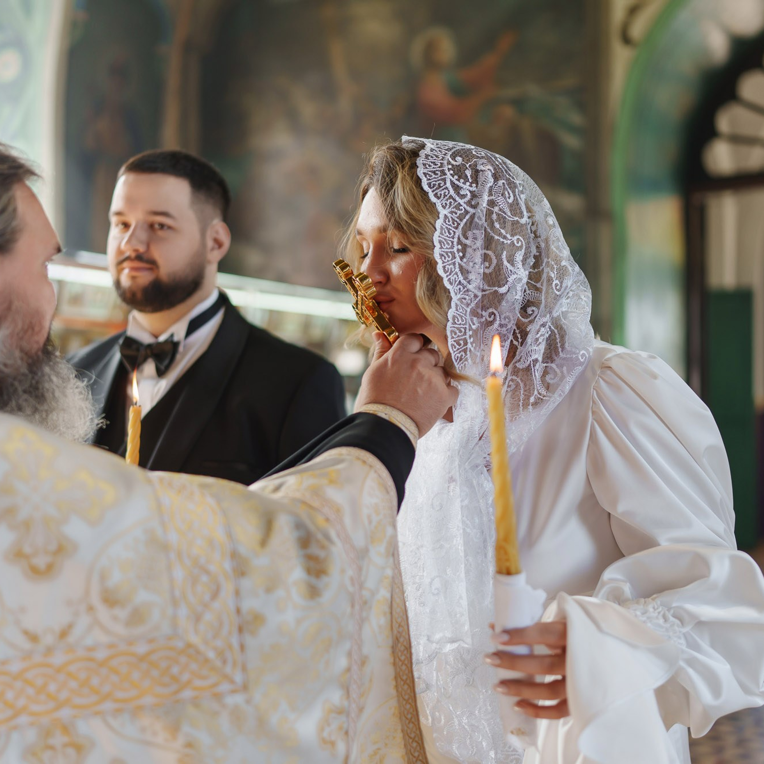 Невеста целует крест во время православного венчания
