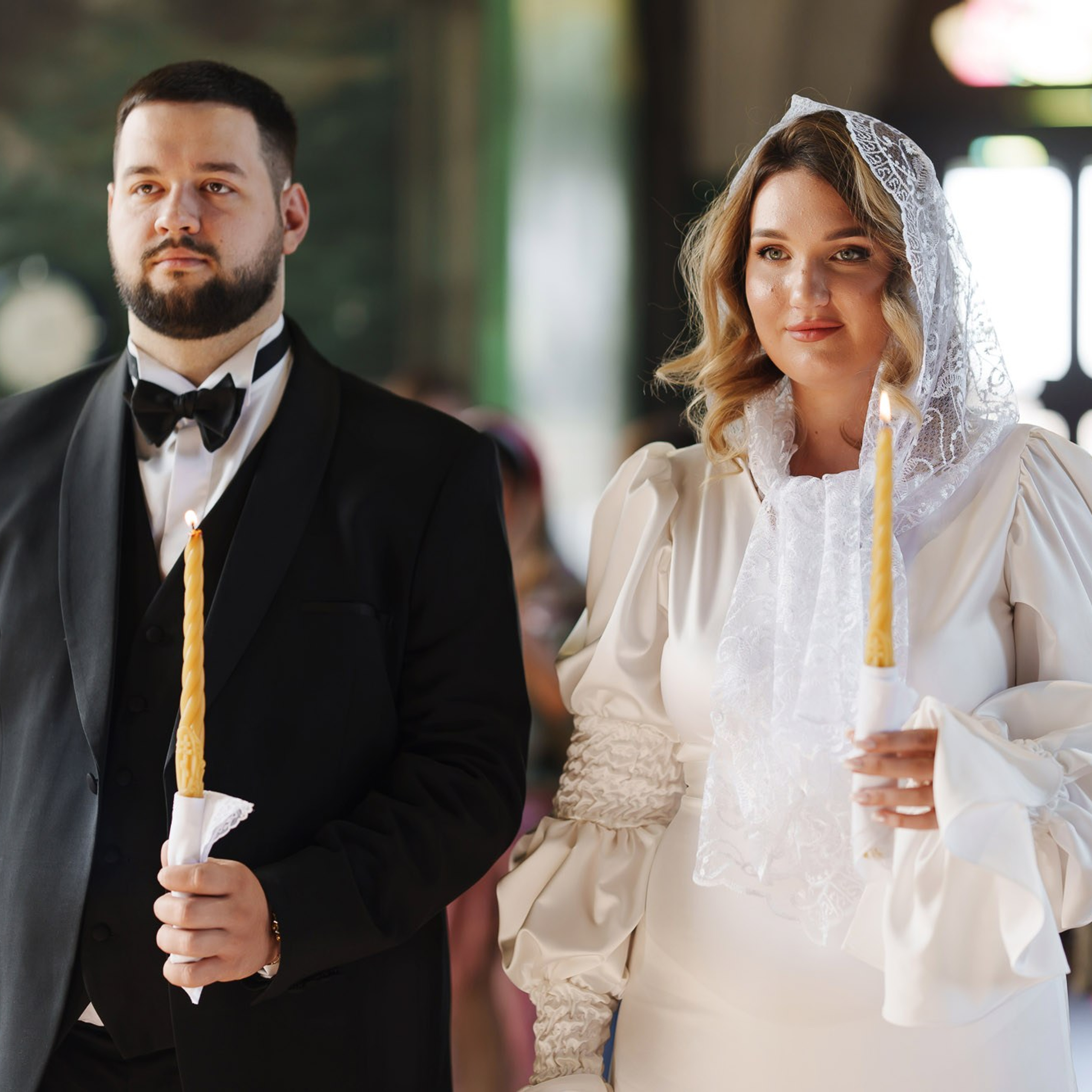 Жених и невеста со свечами во время православного венчания в храме