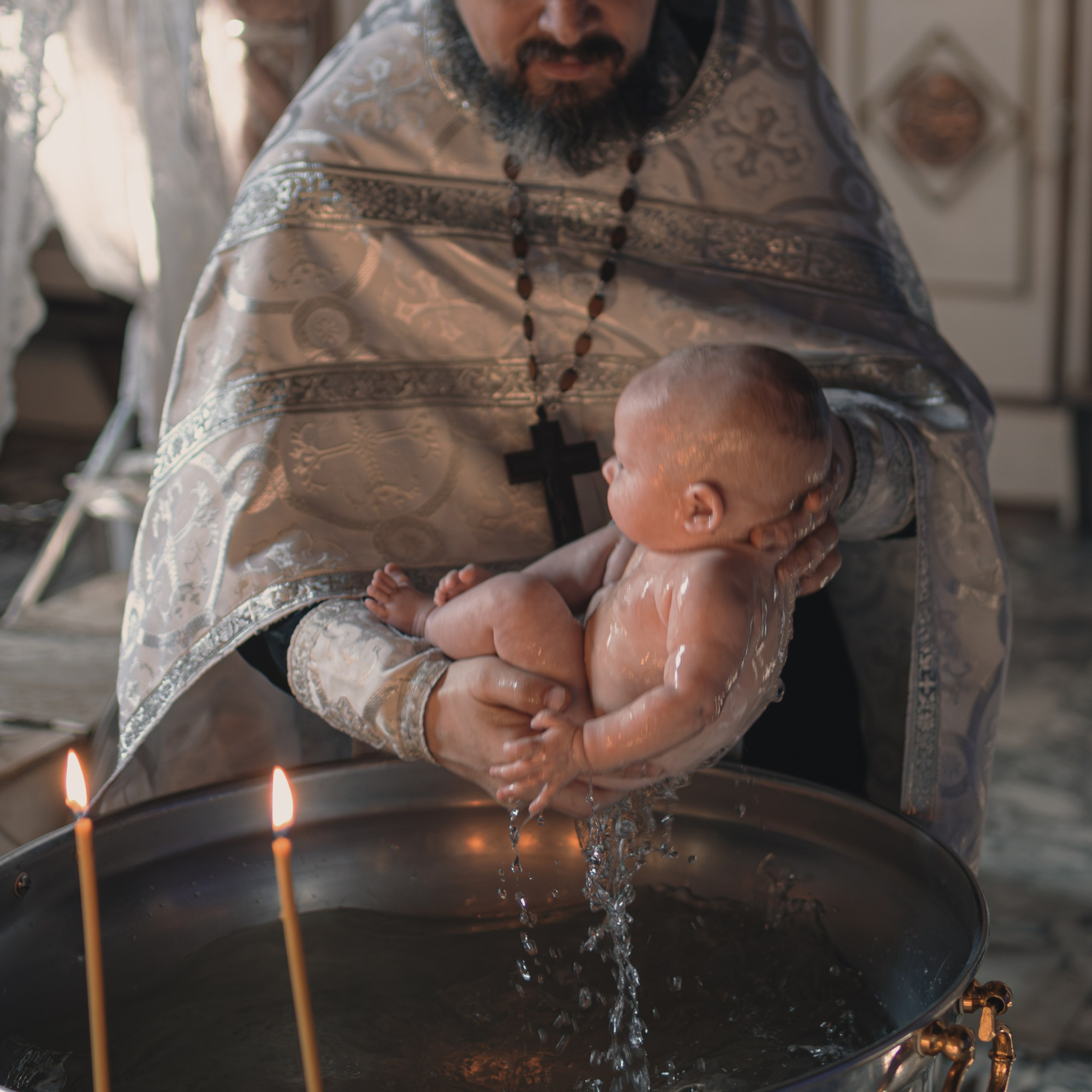 Момент Крещения — священник окунает ребёнка в святую воду купели. Символ чистоты и новой жизни.