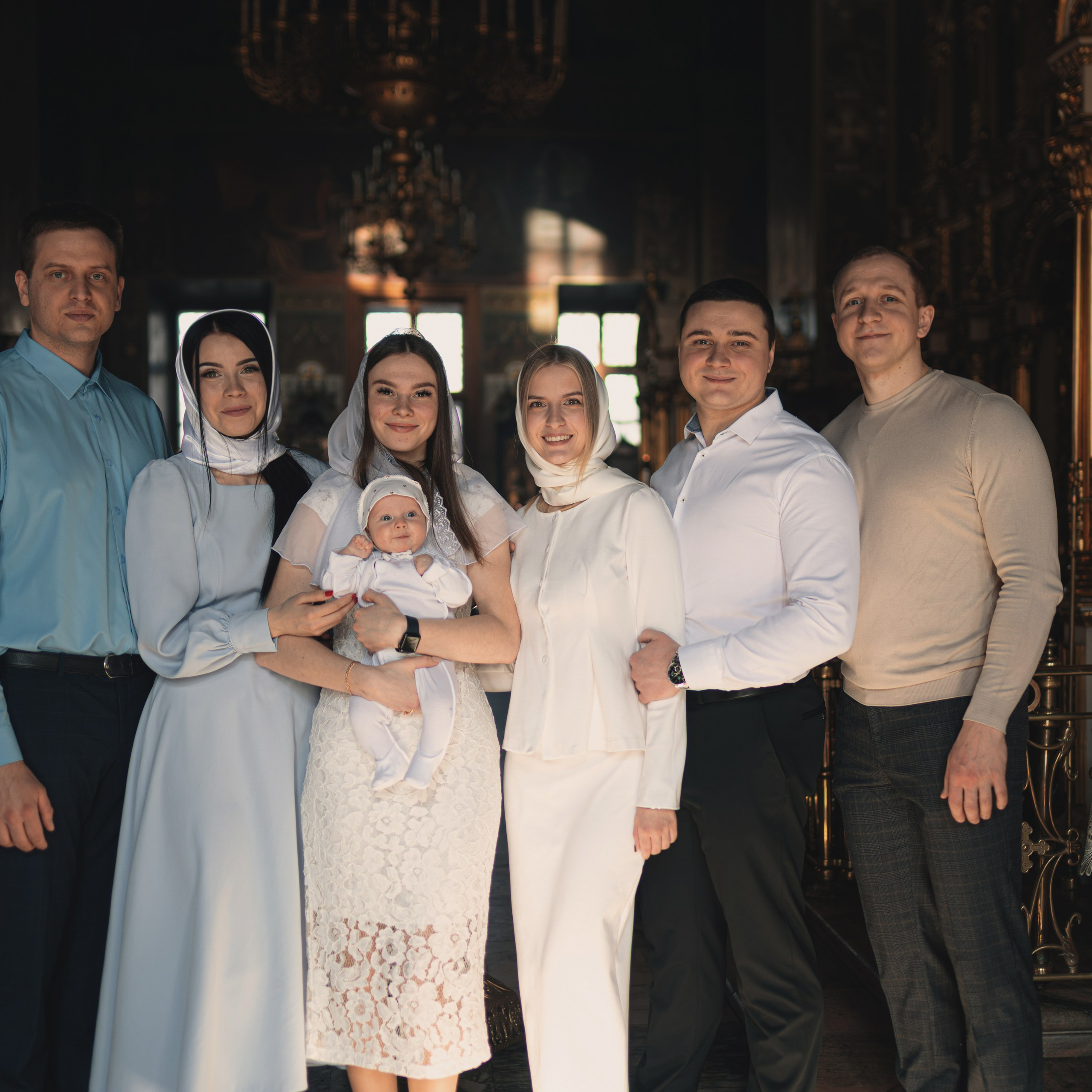 Родители и крёстные вместе с ребёнком у алтаря после Таинства Крещения.