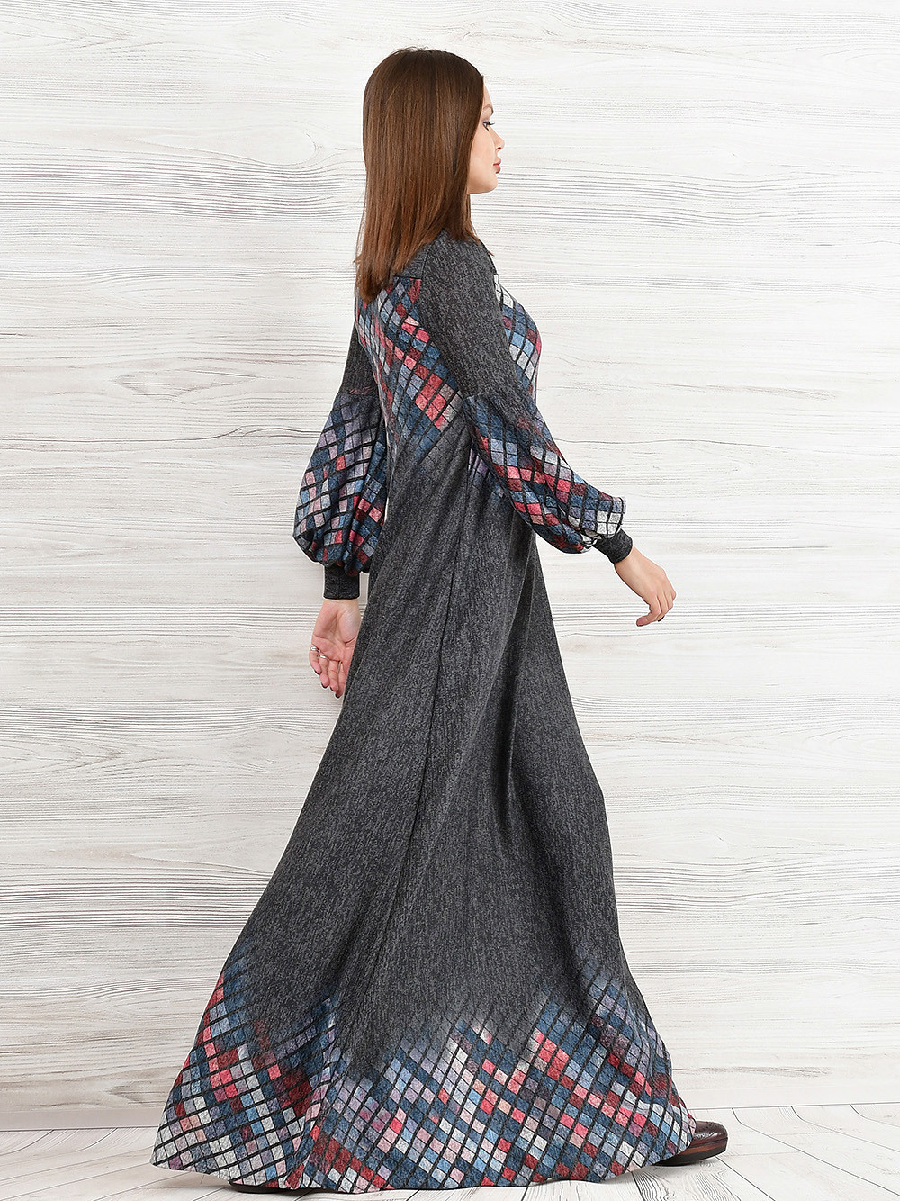 Модель в сером платье идёт по фотостудии.