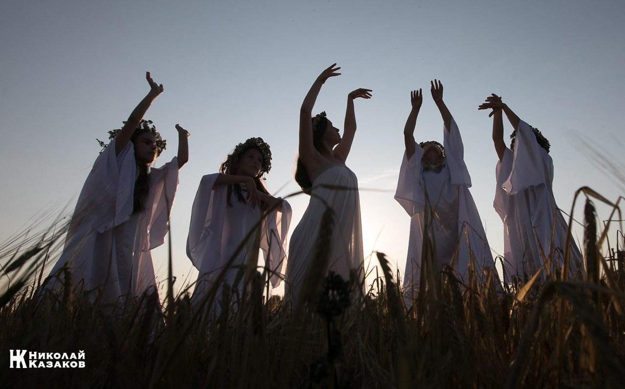 Стройные девочки подростки танцуют в пшеничном поле во время фотосессии на закате.