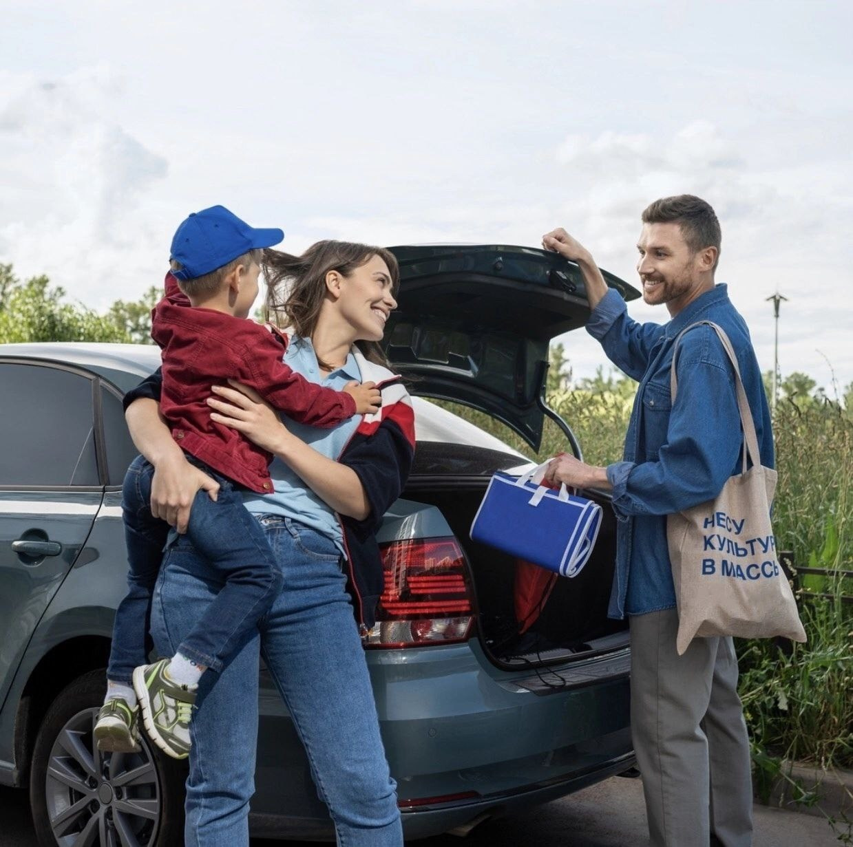 Мужчина и мама с ребенком разгружают багажник машины