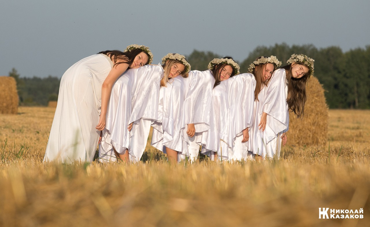 Стройные девочки подростки танцуют в пшеничном поле во время фотосессии на закате.