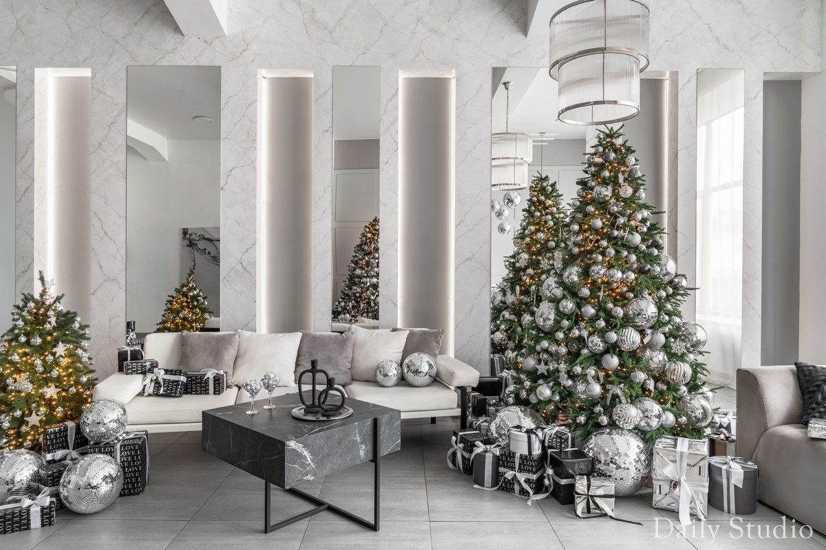 новогодний декор в студии: две елки. белый диван, мраморная стена и зеркала