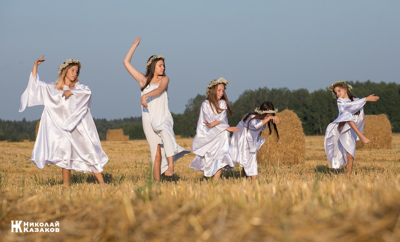 Стройные девочки подростки танцуют в пшеничном поле во время фотосессии на закате.