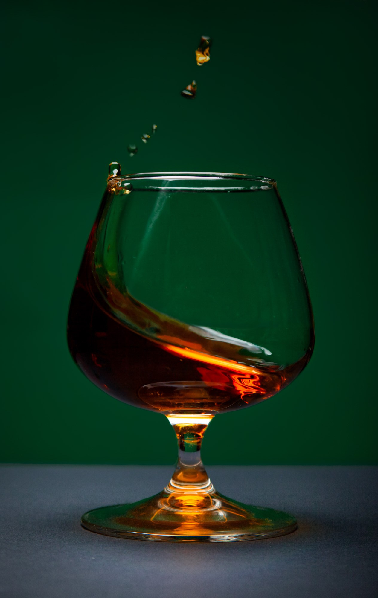 капли коньяка янтарного цвета играют в бокале