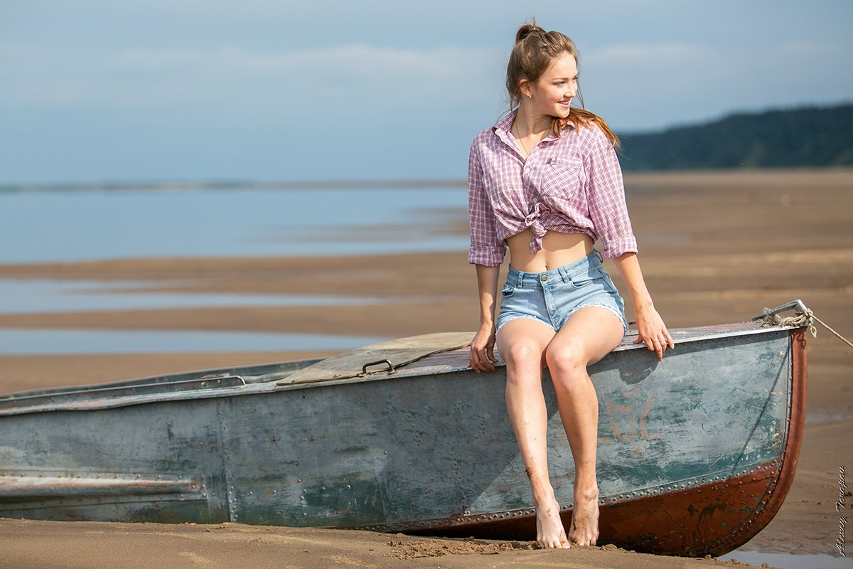 Молодая девушка сидит на лодке на берегу реки Печора