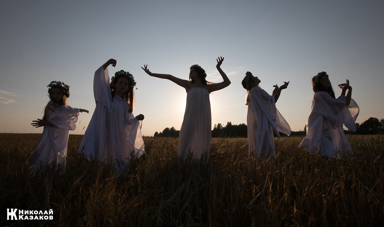Стройные девочки подростки танцуют в пшеничном поле во время фотосессии на закате.
